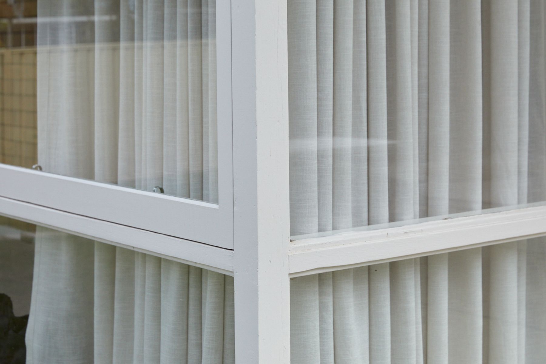 Corner of windows with sheer white curtains inside