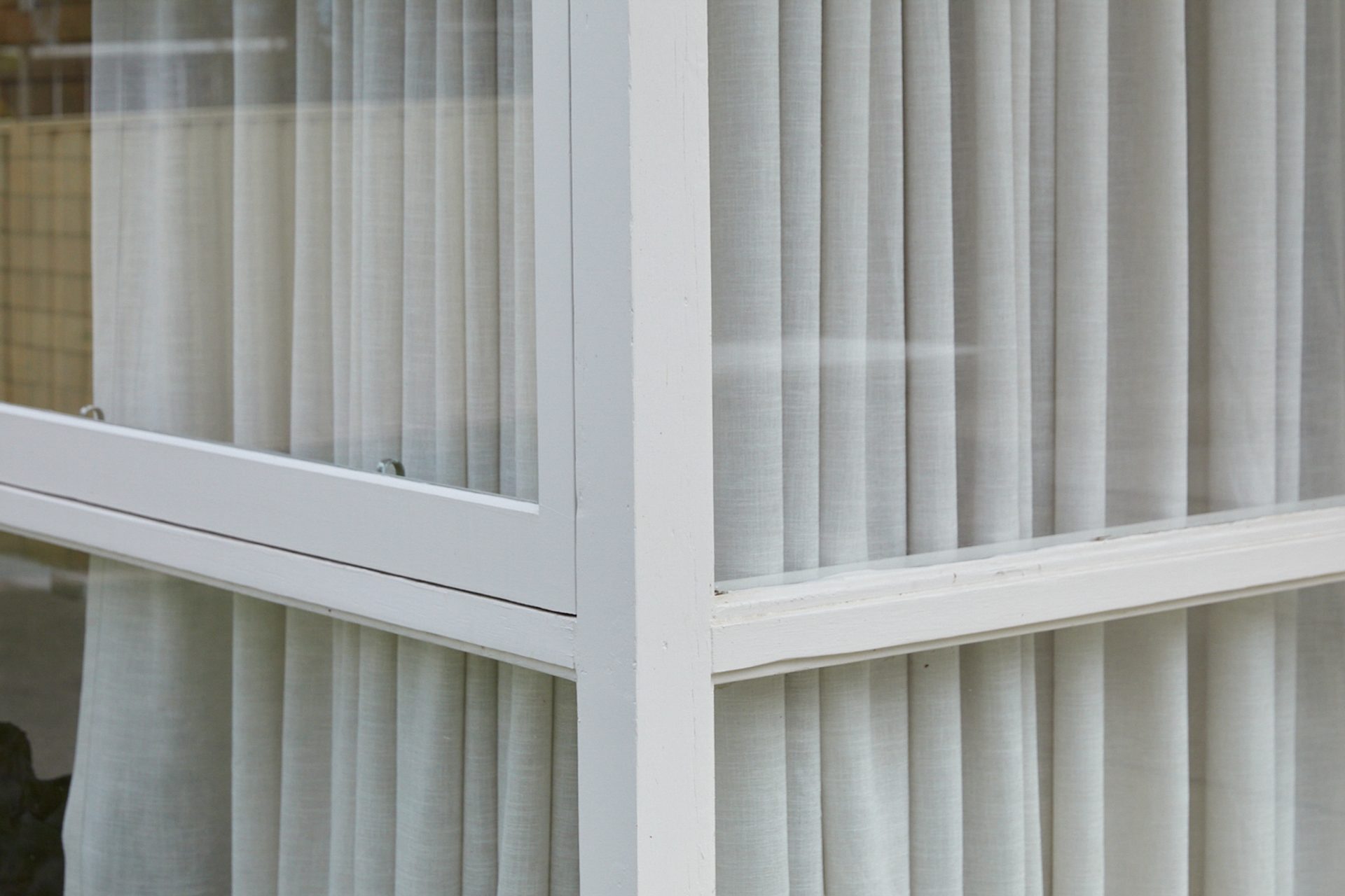 Corner of windows with sheer white curtains inside