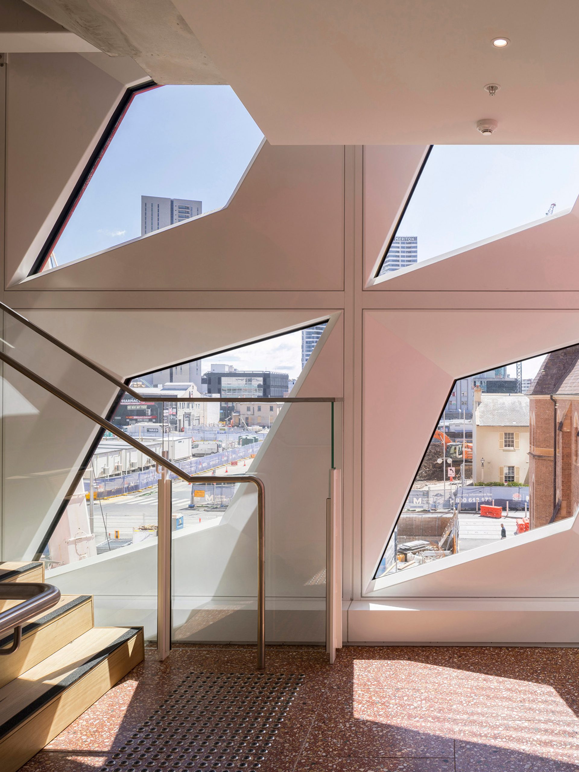 Four diamond-shaped windows in a white wall of PHIVE allow light into a staircase