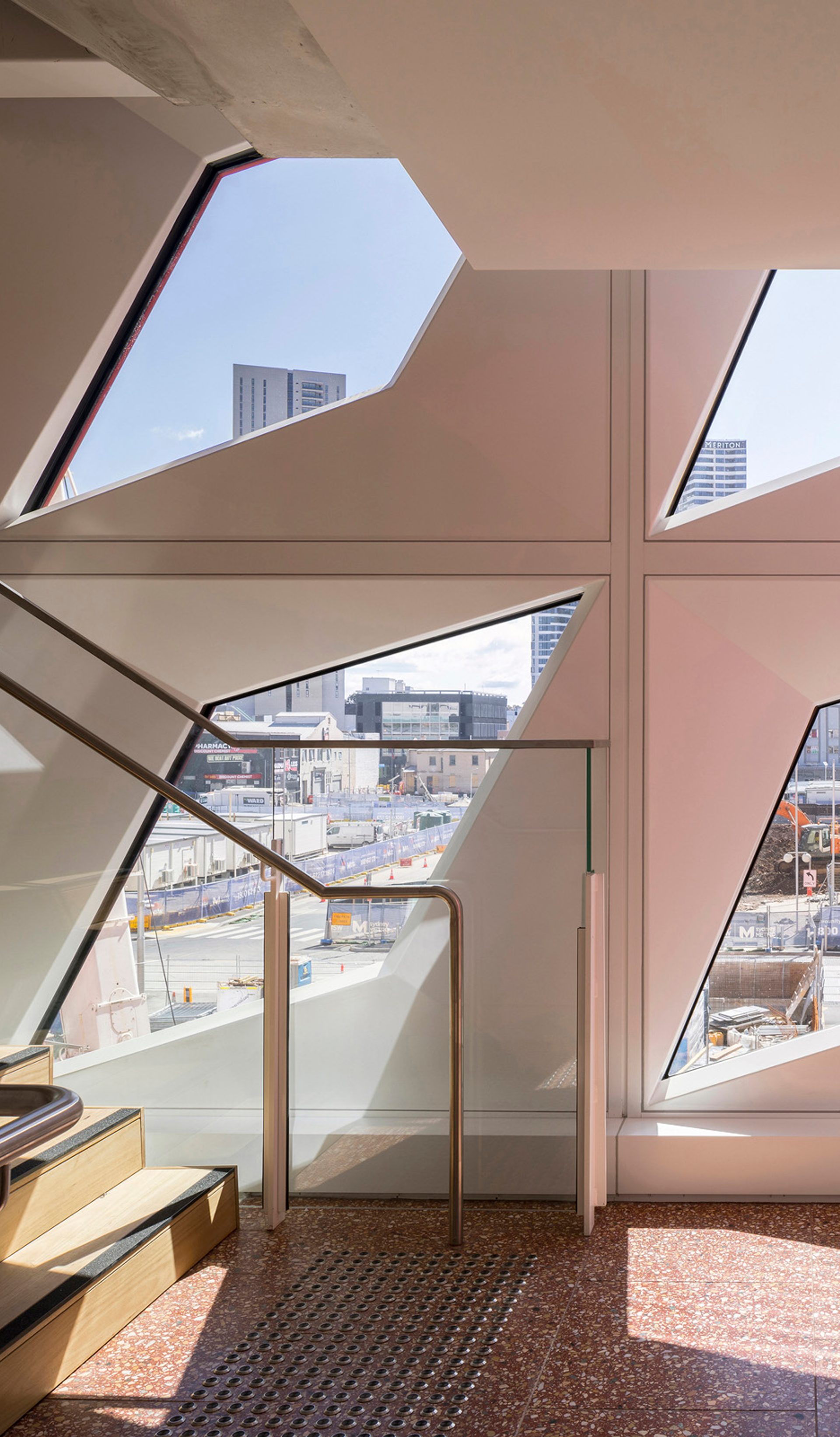 Four diamond-shaped windows in a white wall of PHIVE allow light into a staircase