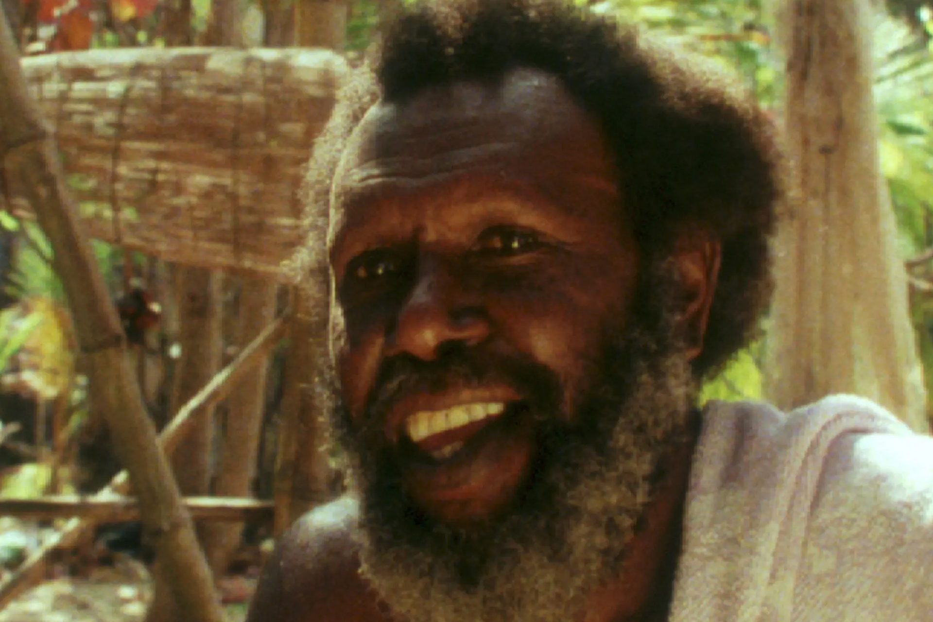 Koiki Mabo sitting within bamboo and sand backgorund.