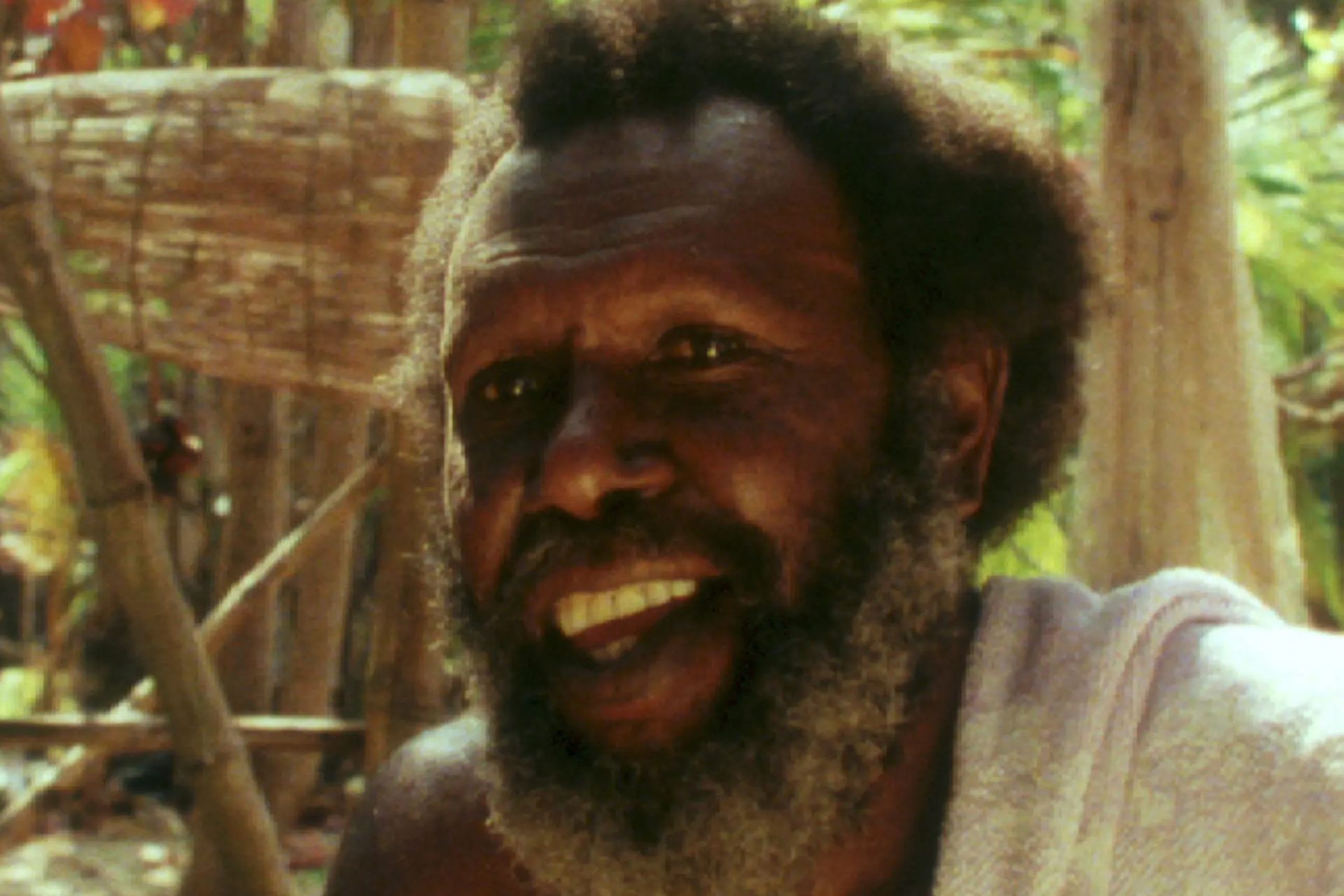 Koiki Mabo sitting within bamboo and sand backgorund.