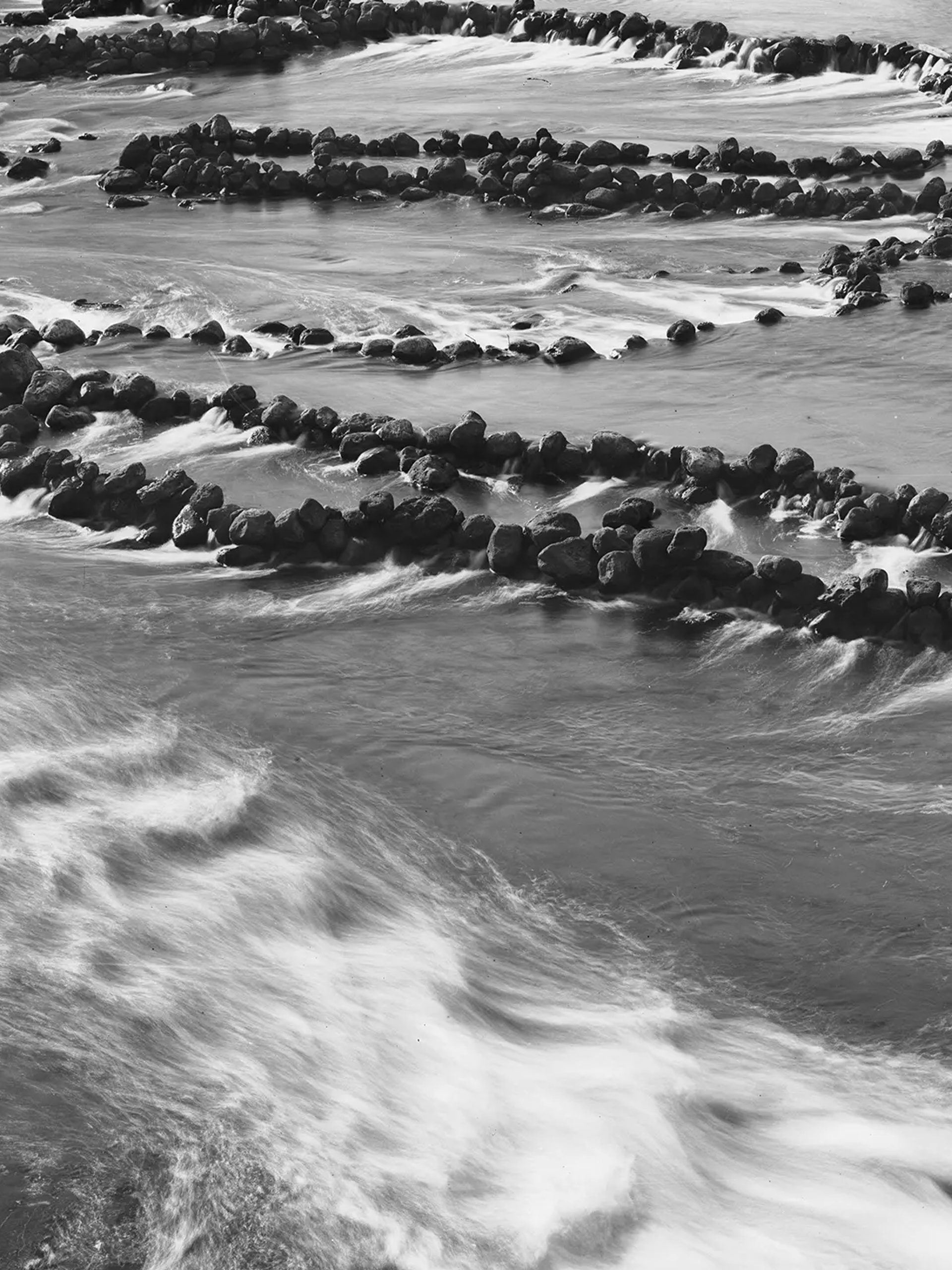 A silver gelatin dry plate glass negative in landscape format. A silver gelatin dry plate glass negative in landscape format. The image shows fish traps in a section of the Darling River. The fish traps consist of low stone walls constructed on the river bed. The walls are arranged to form cul de sacs that trap the fish. The Tyrrell Collection Inventory records the above caption but does not attribute the negative to a studio.