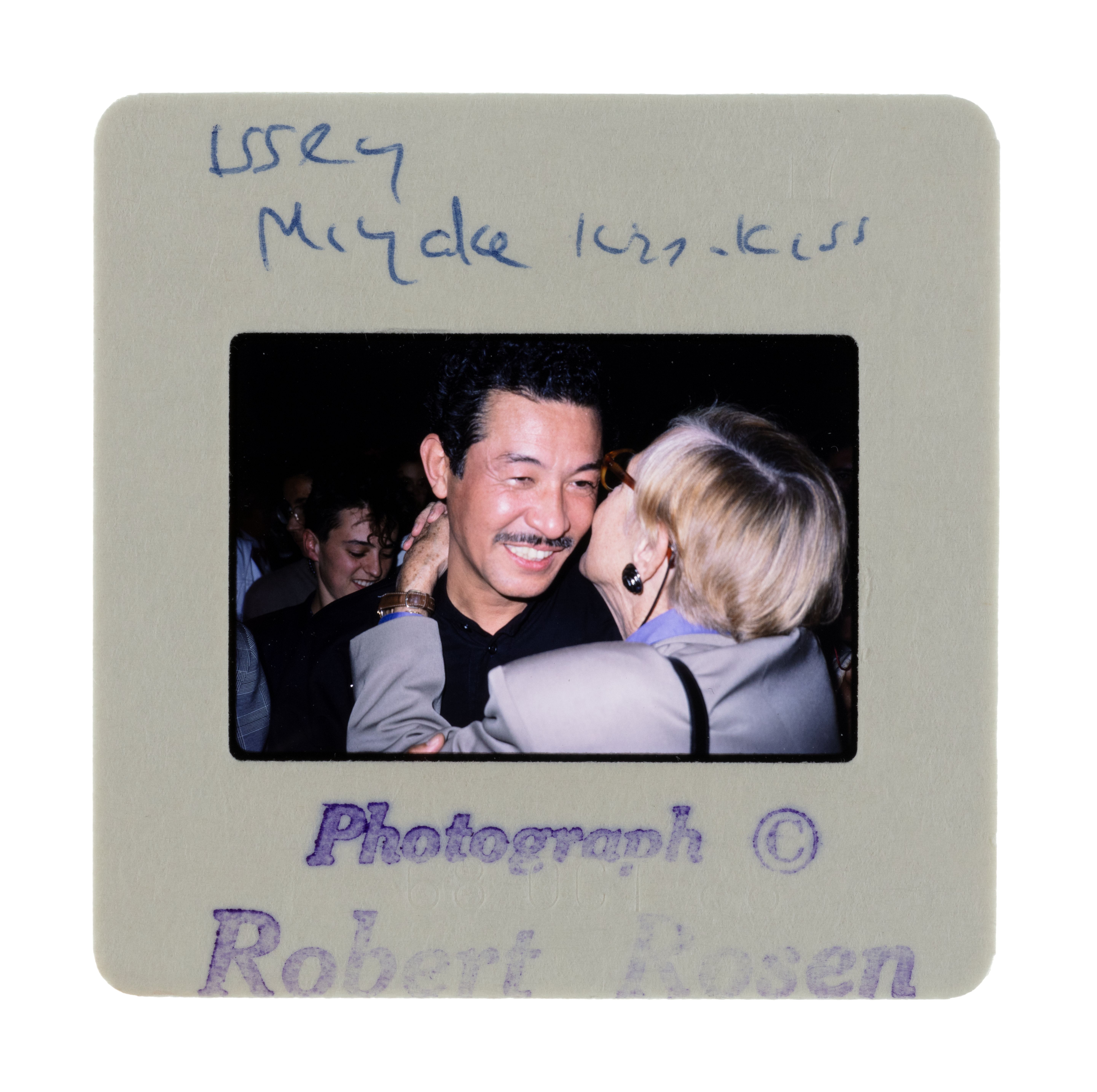Photo positive slide of 'Issey Miyake, Paris, S.S.89', fashion, Runway Shows, photographed by Robert Rosen, London and Paris, 1978-2000. A man (Issey Miyake) smiling while being kissed on the cheek by another figure.