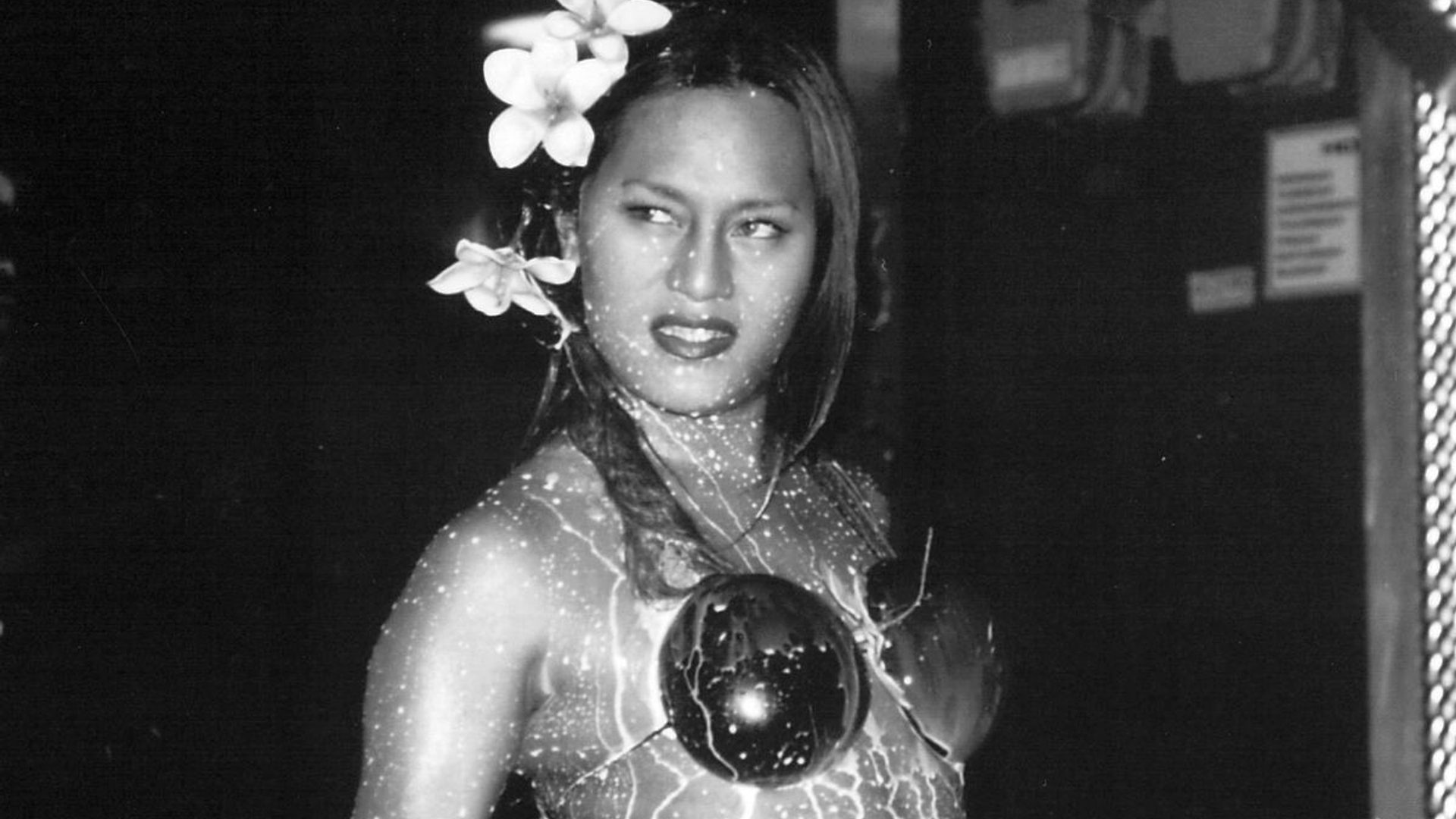 A figure looks off to the side with a grimace. They have two flowers in their hair.