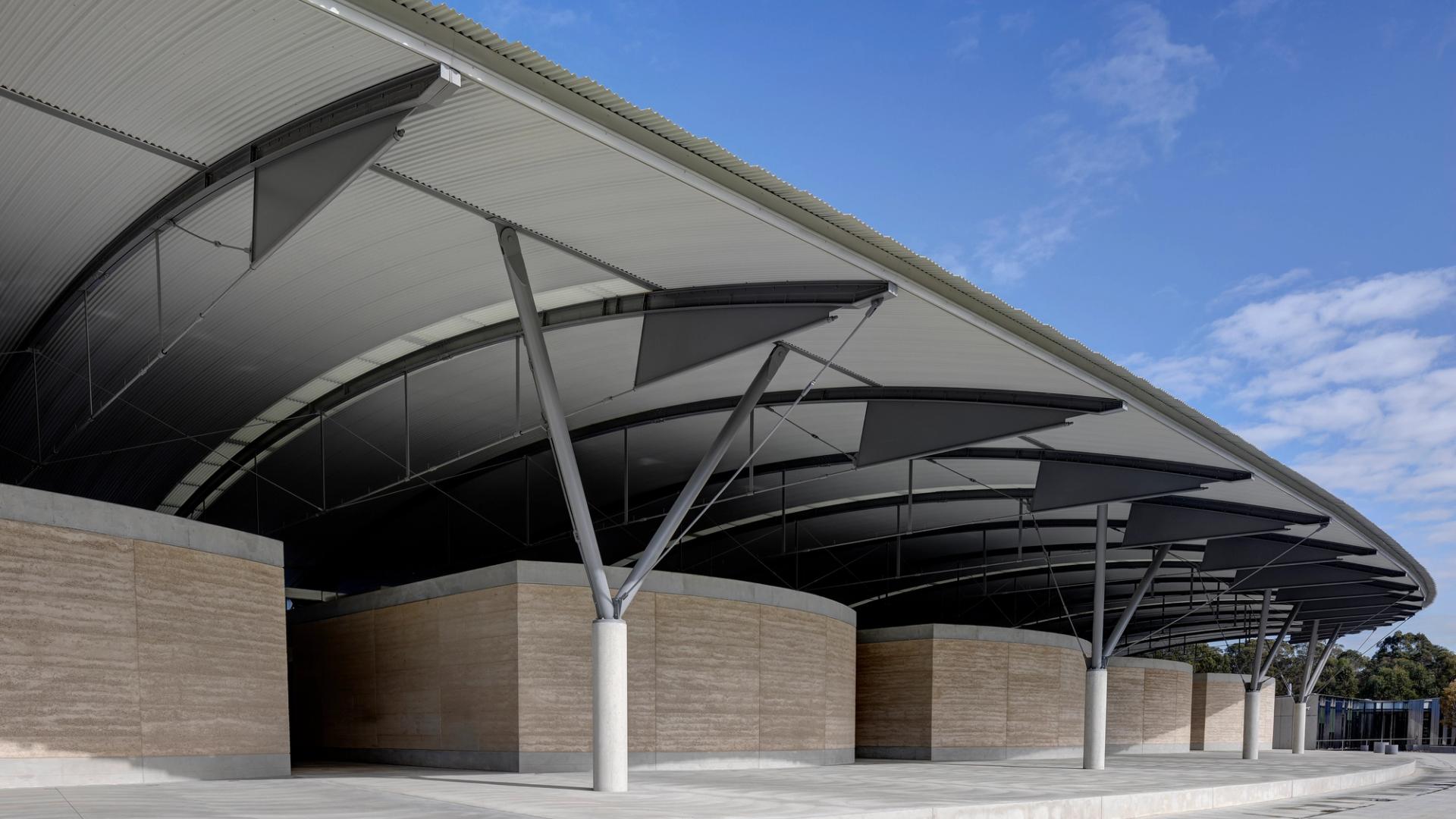The interior steel structure of the National Herbarium’s roof above low stone walls, supported by a Y-shaped frame.