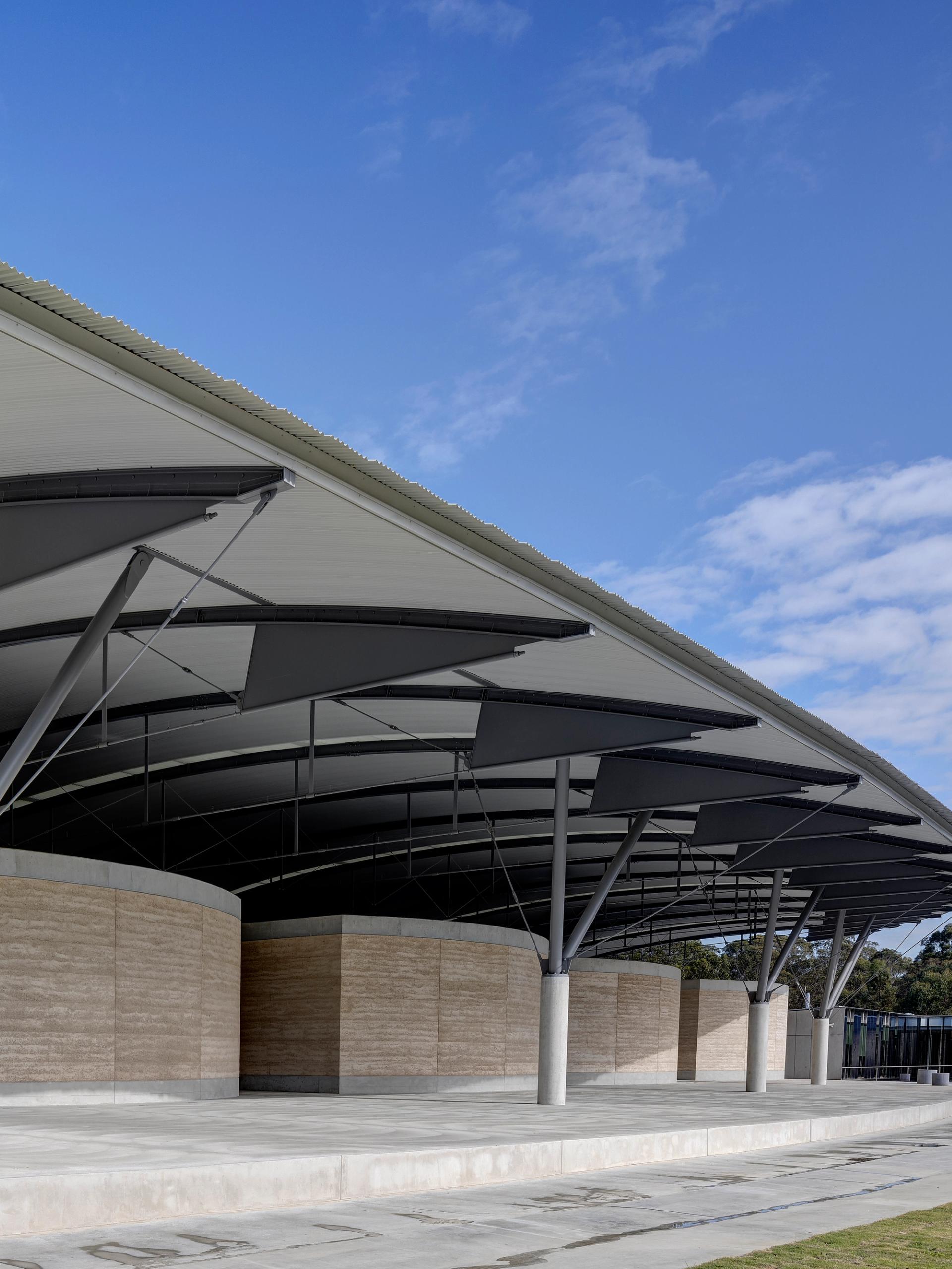 The interior steel structure of the National Herbarium’s roof above low stone walls, supported by a Y-shaped frame.