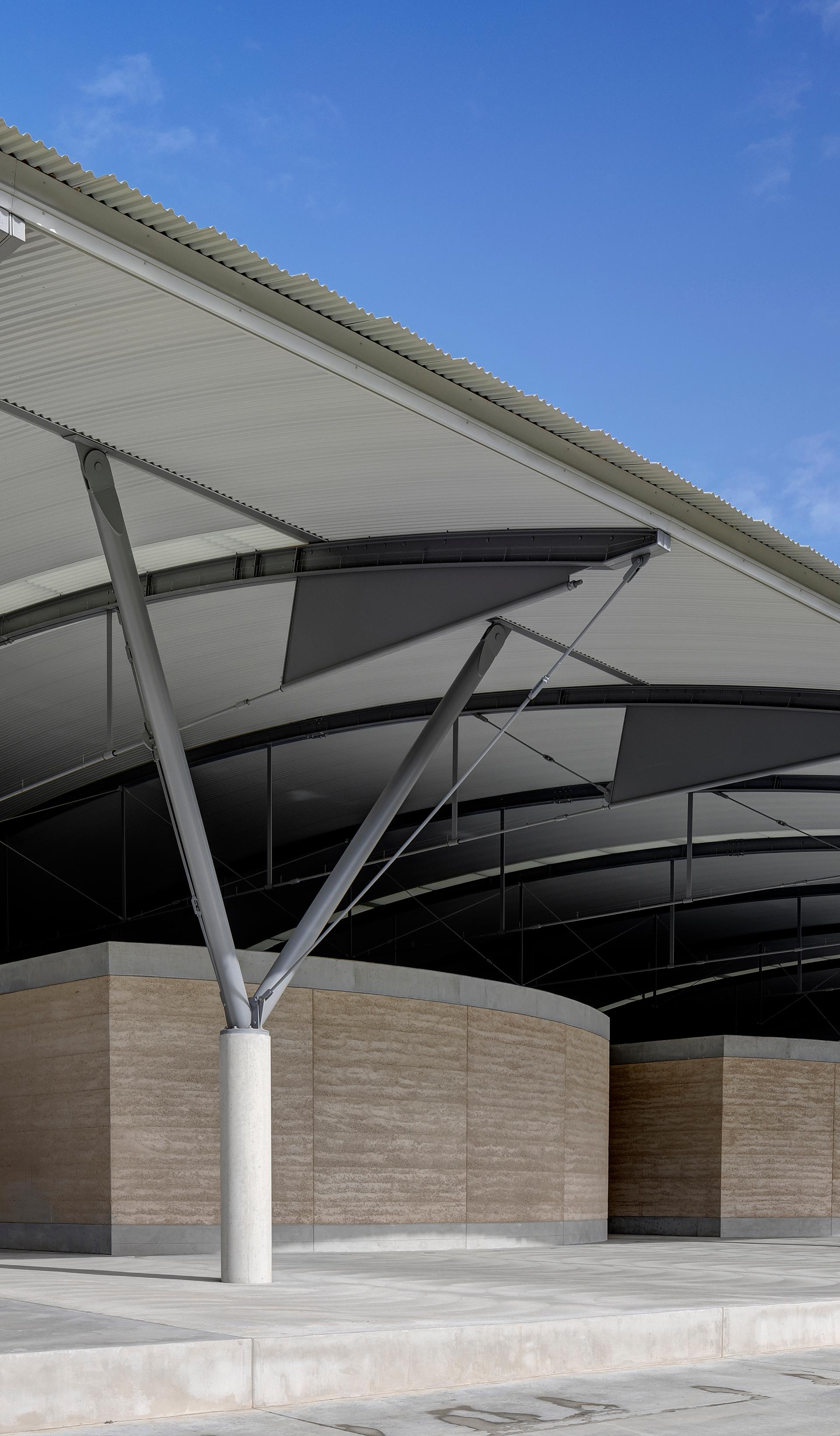 The interior steel structure of the National Herbarium’s roof above low stone walls, supported by a Y-shaped frame.