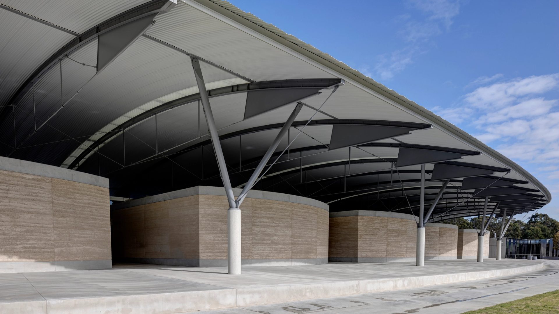 The interior steel structure of the National Herbarium’s roof above low stone walls, supported by a Y-shaped frame.
