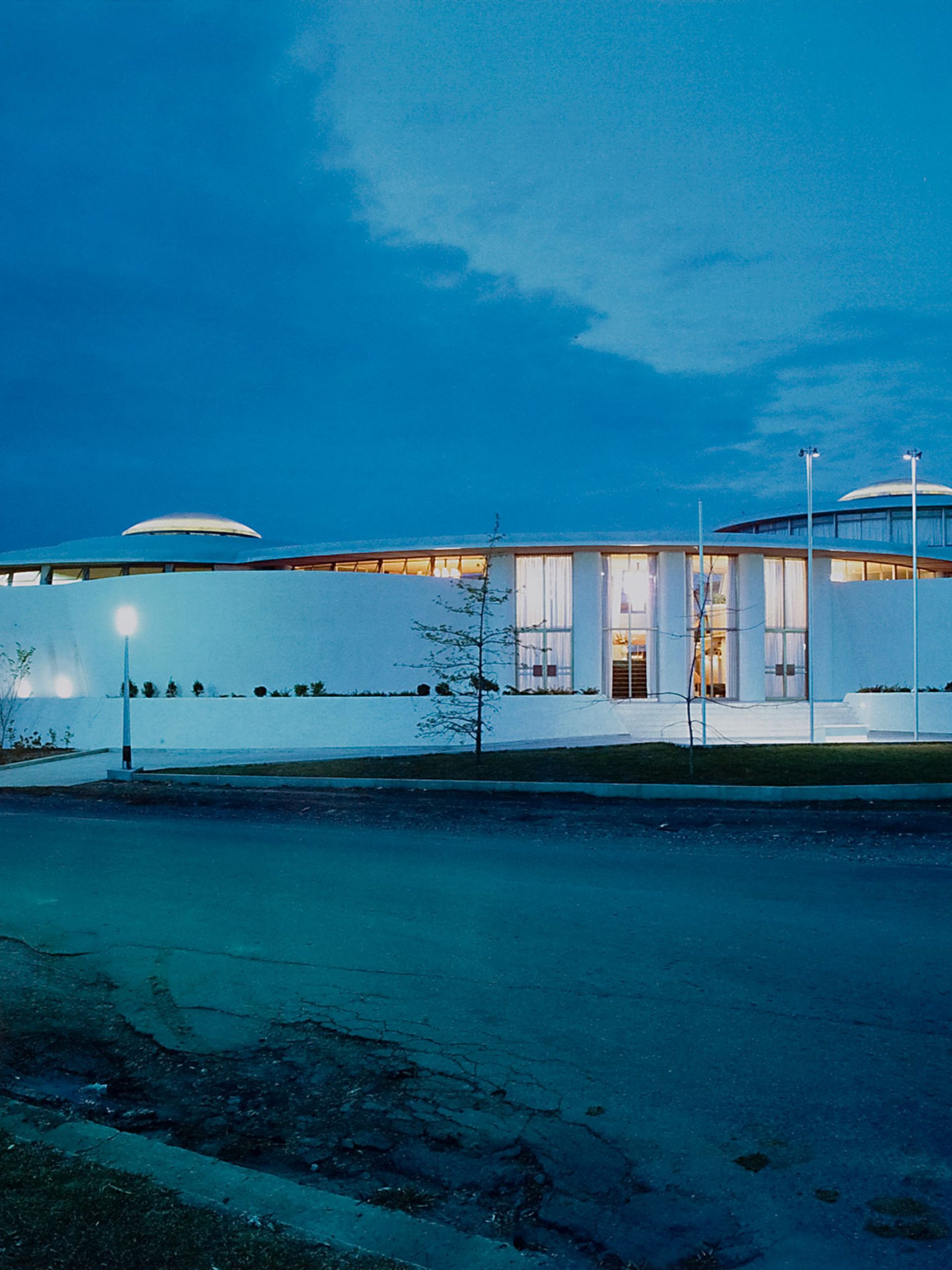 Gloss colour photographic print of the exterior of a white single level 1960s building, the Granville Returned Servicemen's Leagues Club photographed at night. The photograph has a small, embossed icon in the left hand corner with the text 'Max Dupain and Associates Archival Print'.
