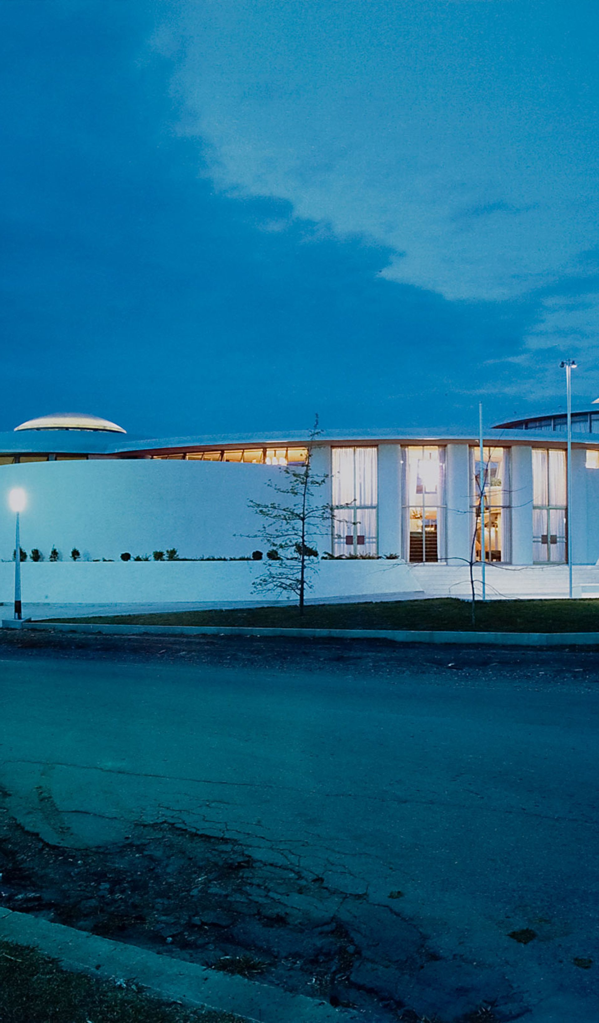 Gloss colour photographic print of the exterior of a white single level 1960s building, the Granville Returned Servicemen's Leagues Club photographed at night. The photograph has a small, embossed icon in the left hand corner with the text 'Max Dupain and Associates Archival Print'.
