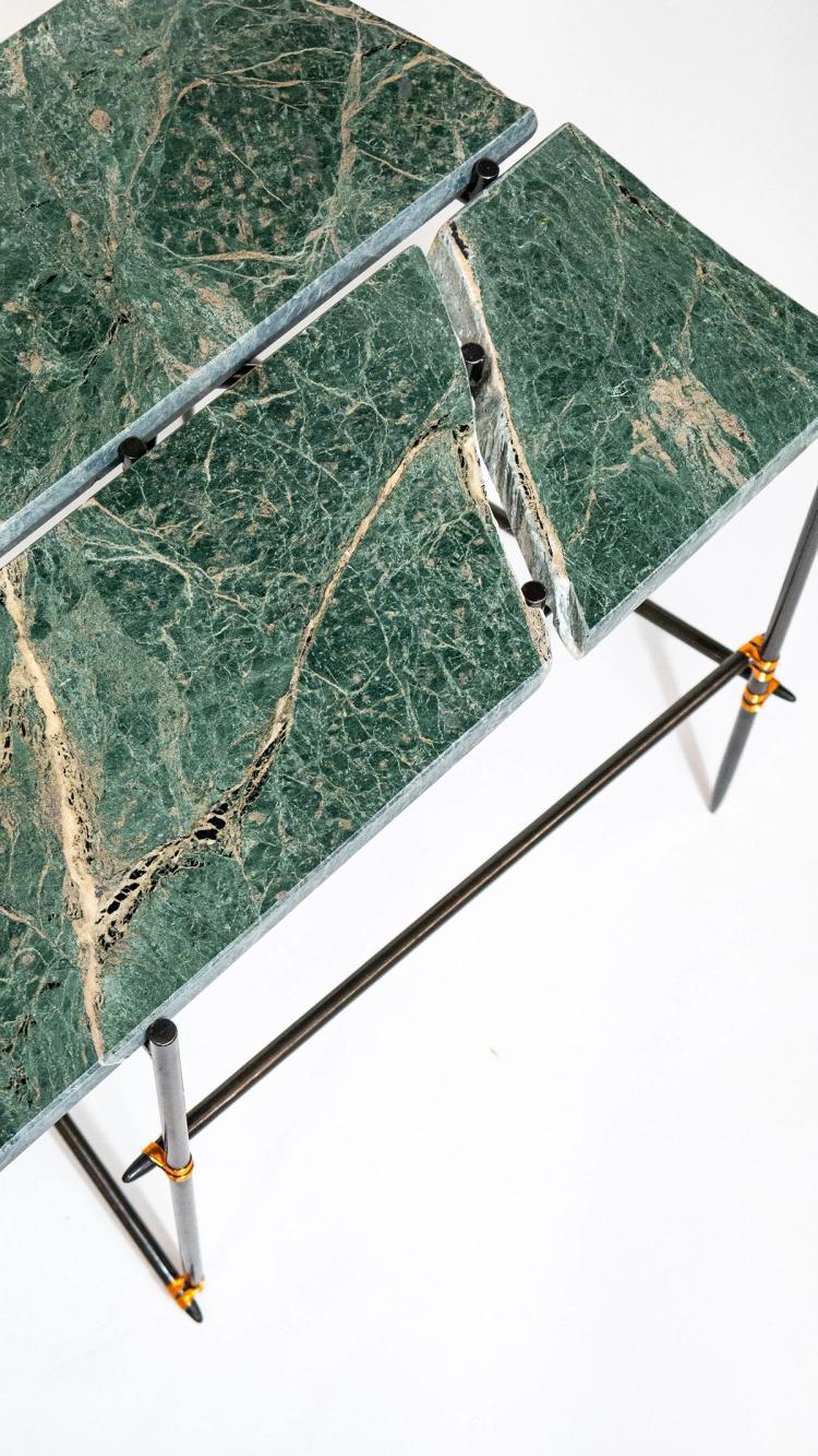 A close up image of the top of a green marbled table with black legs.