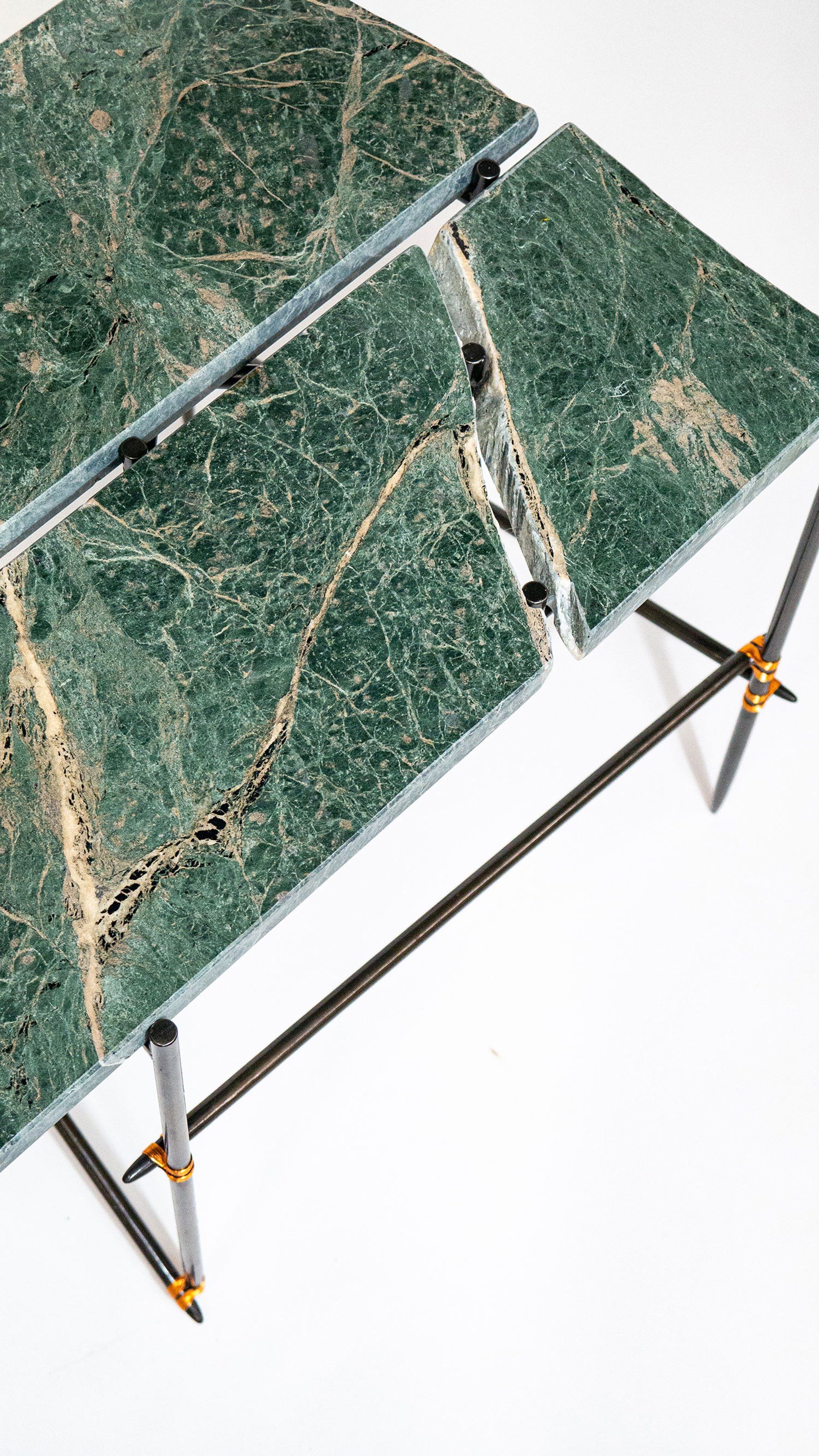 A close up image of the top of a green marbled table with black legs.