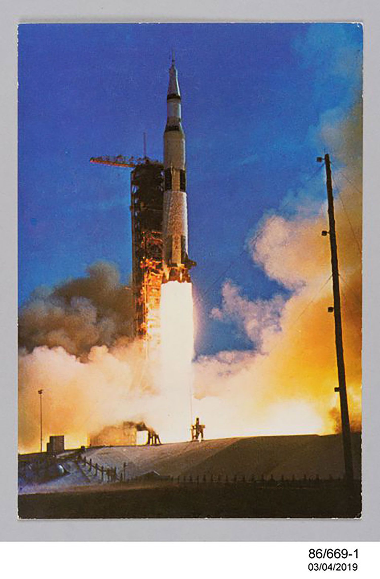 Postcard of a spacecraft launching. Fire is seen below the spacecraft. There is a dark blue night sky behind the spacecraft.