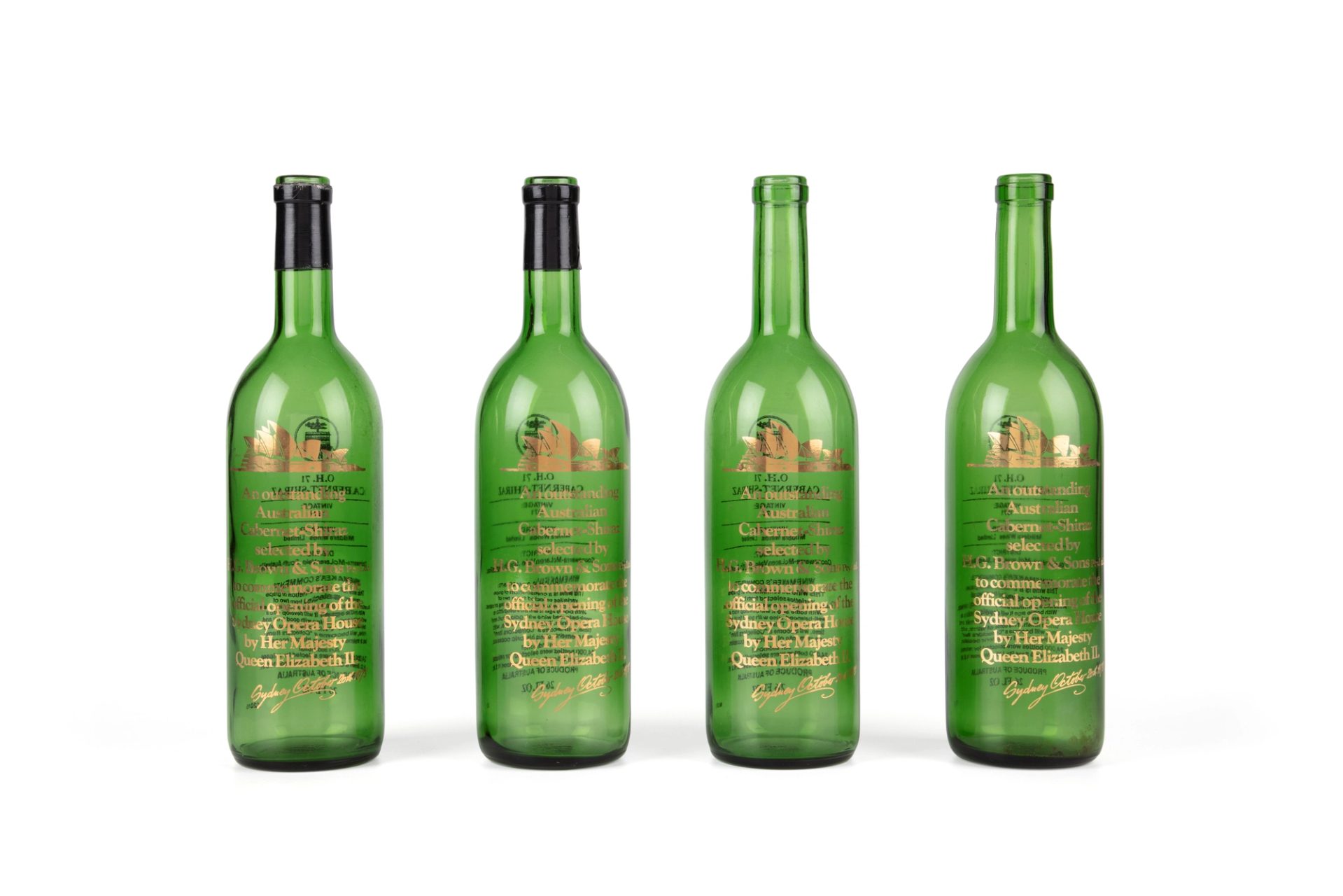 Four green empty wine bottles with matching gold labels