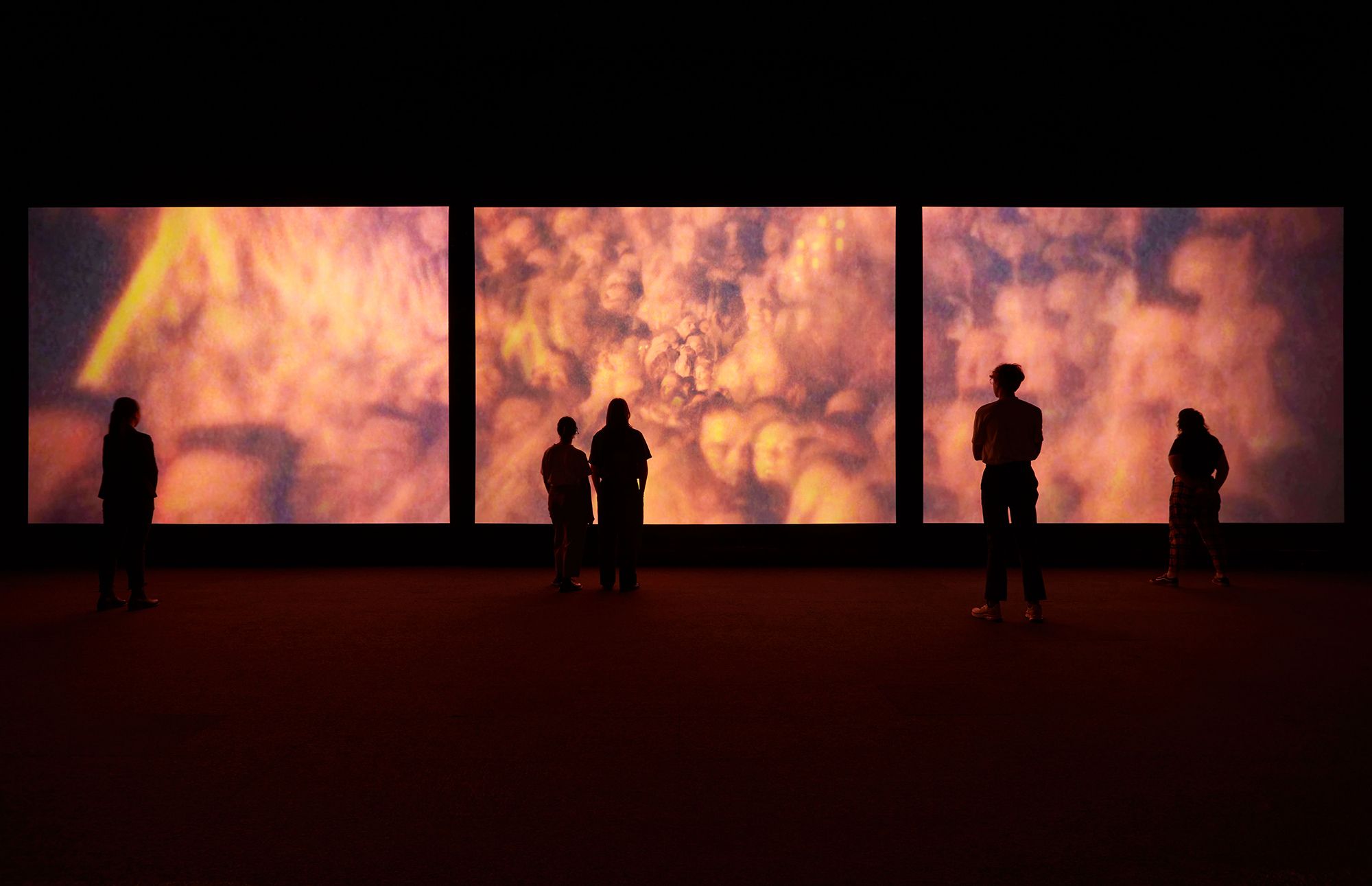 Three large screens in a dark room.