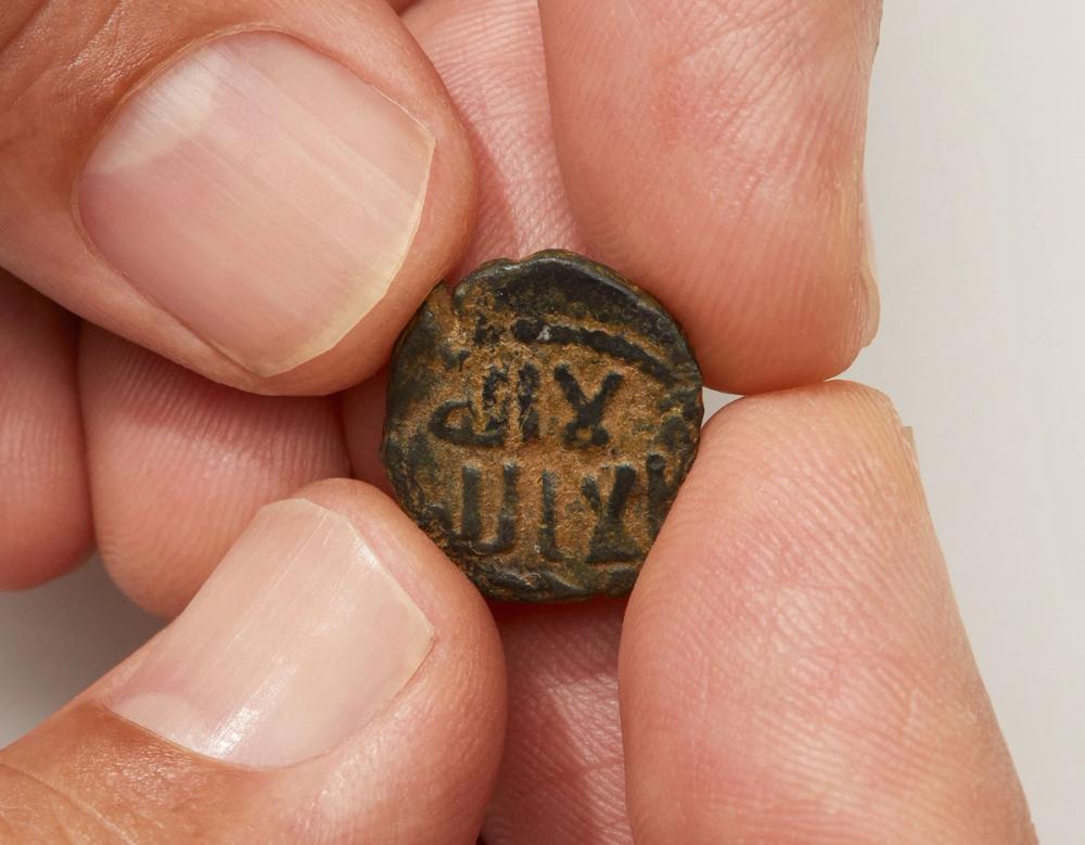 Photograph of ancient coin in fingertips