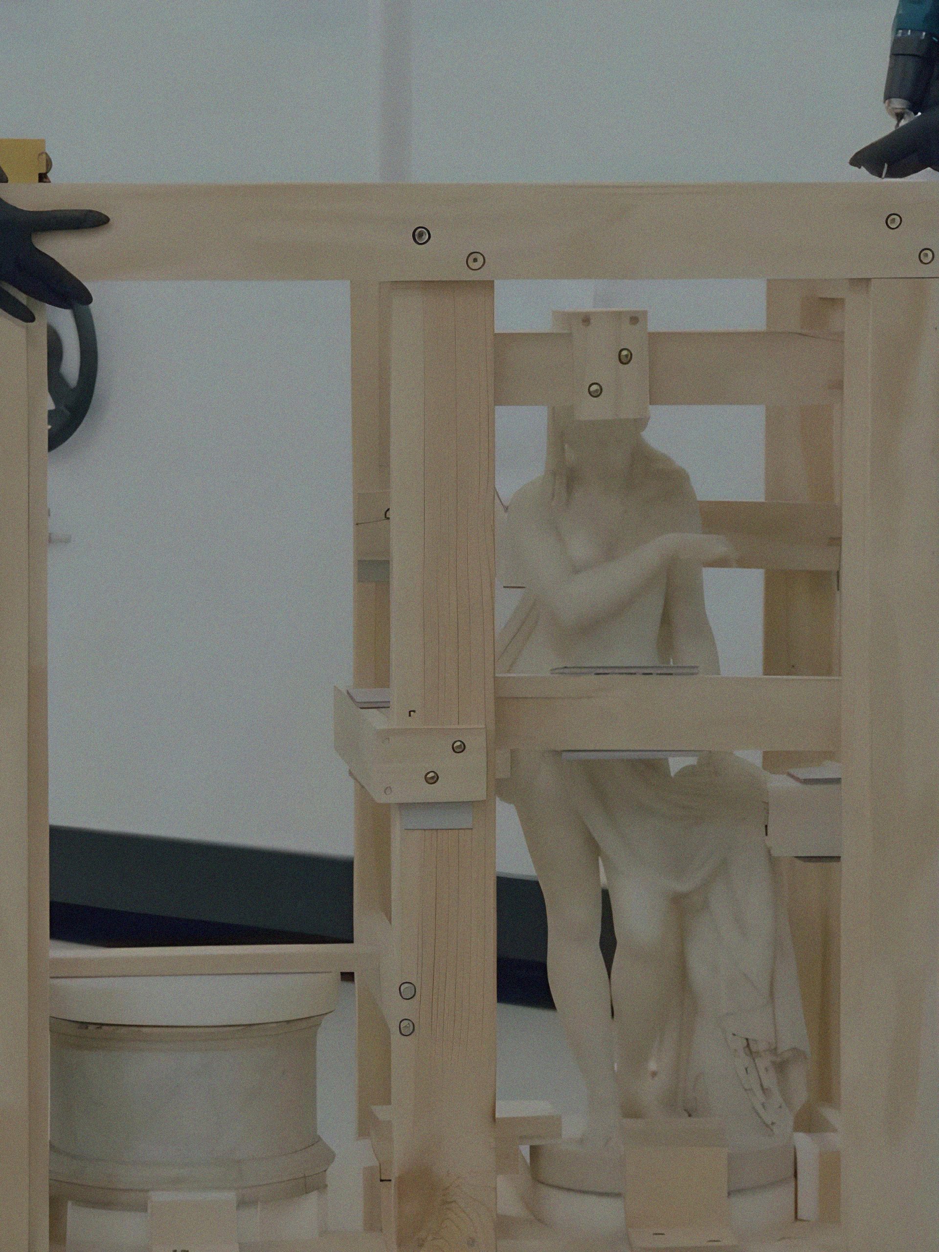 Two people packing a sculpture with secure wooden beams.