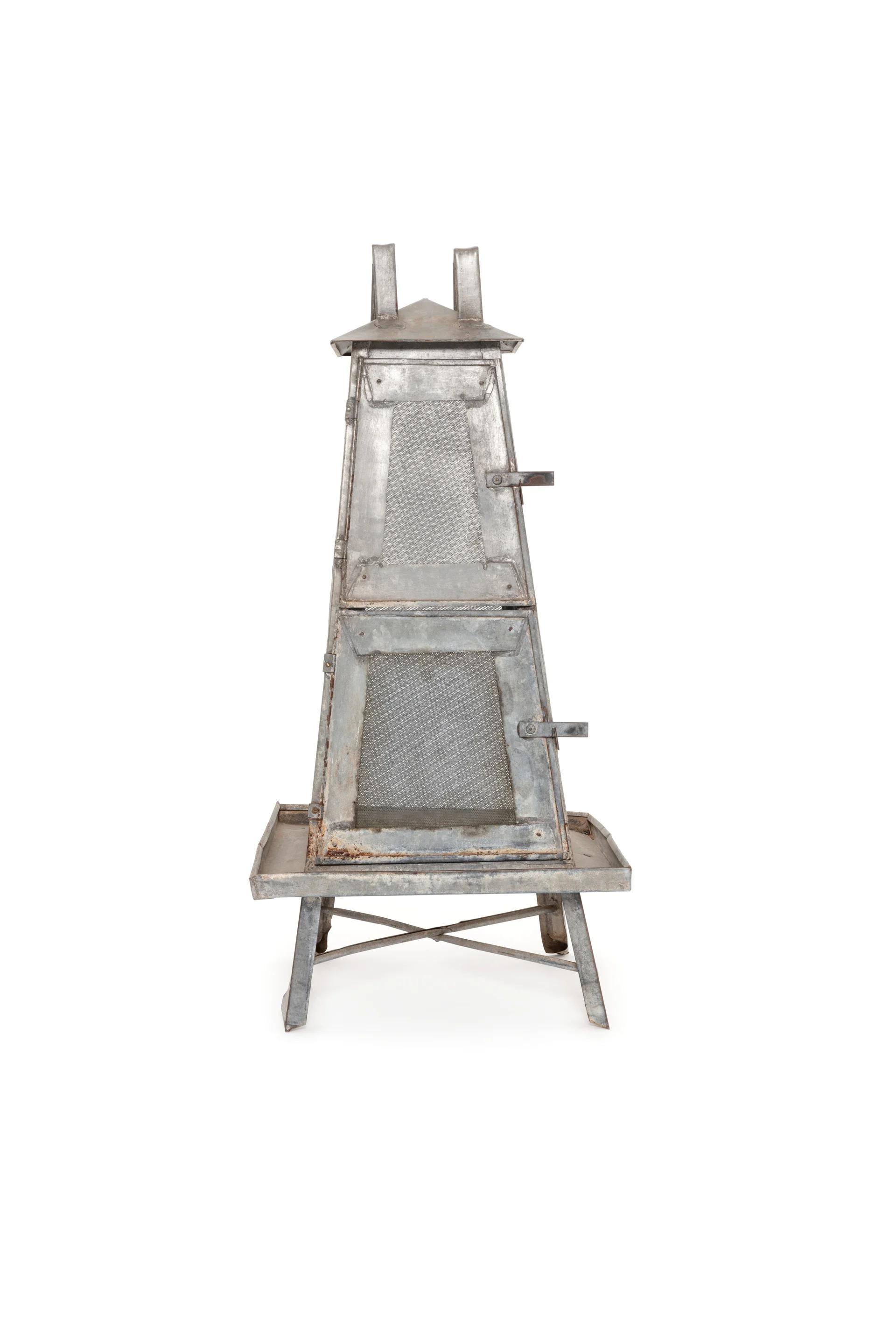 An obelisk-shaped food safe made from metal with two doors and a peaked roof.