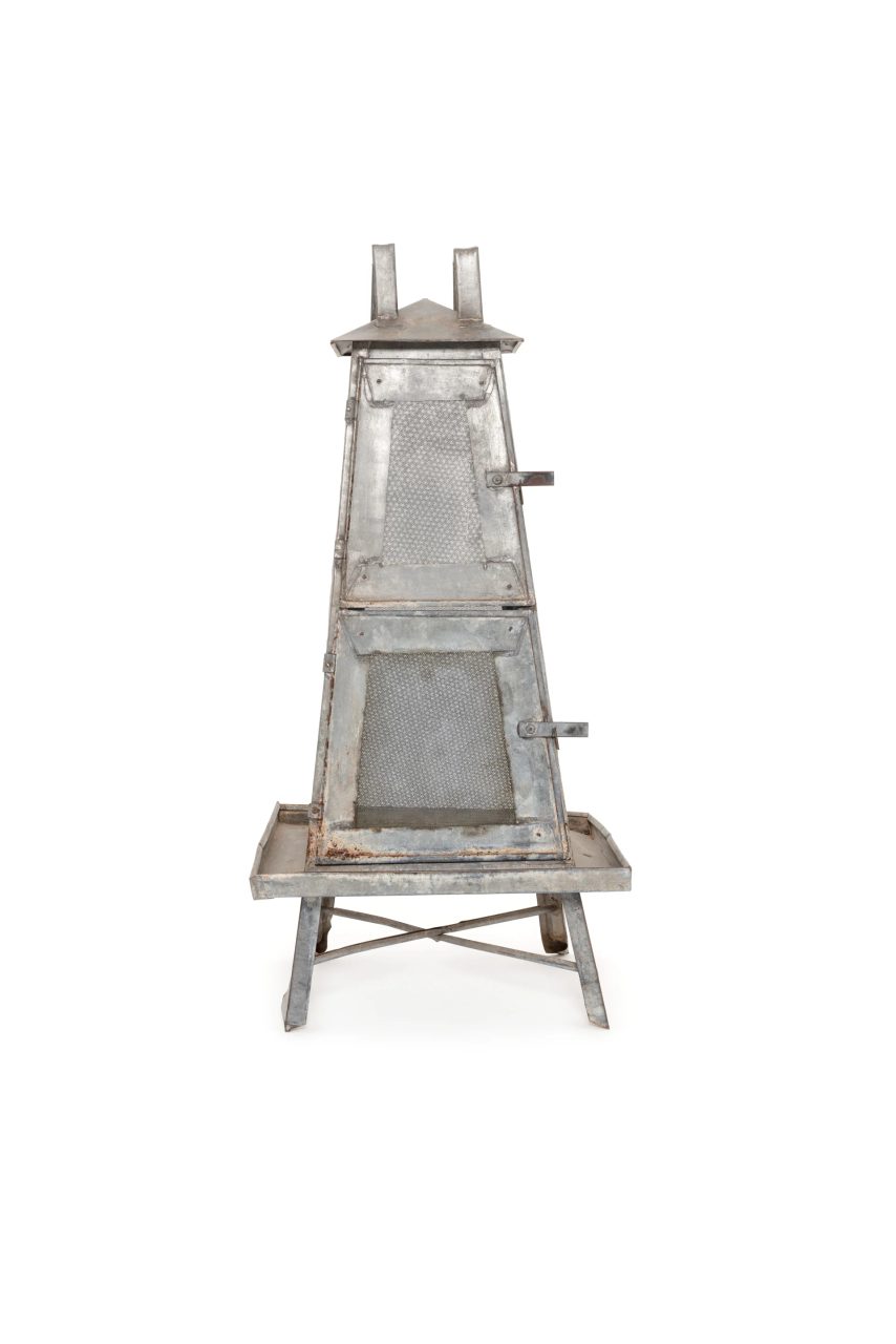 An obelisk-shaped food safe made from metal with two doors and a peaked roof.