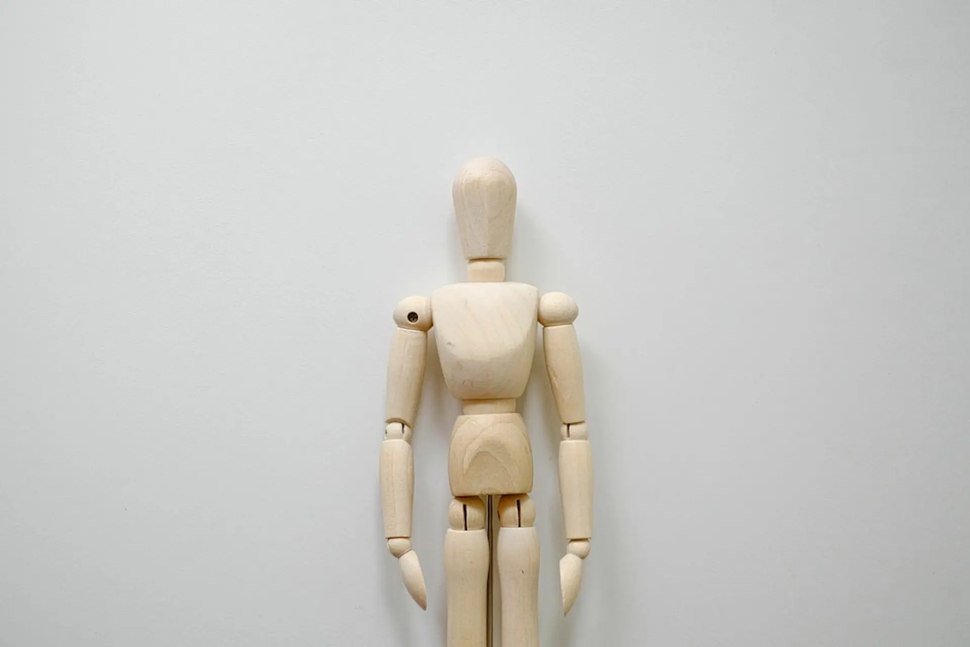 A Practical Blueprint — Design for Augmentation, Not Replacement - a wooden mannequin standing in front of a white wall