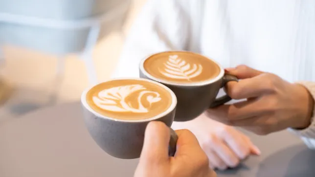 Zwei Cappuccinos mit Latte Art werden aneinander gehalten