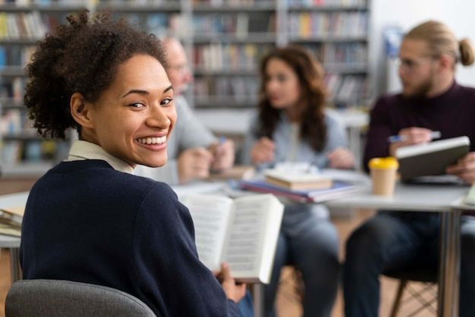 student in library reading and smiling
