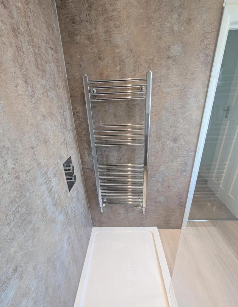 Chrome towel radiator above shower tray