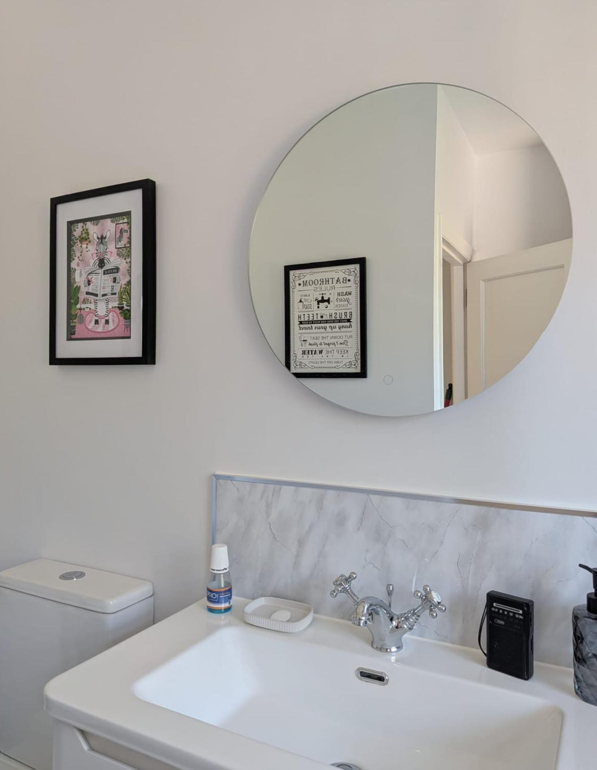Bathroom sink with round mirror and toilet