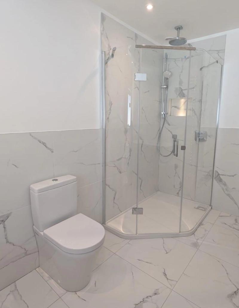 Marble bathroom with corner shower and toilet