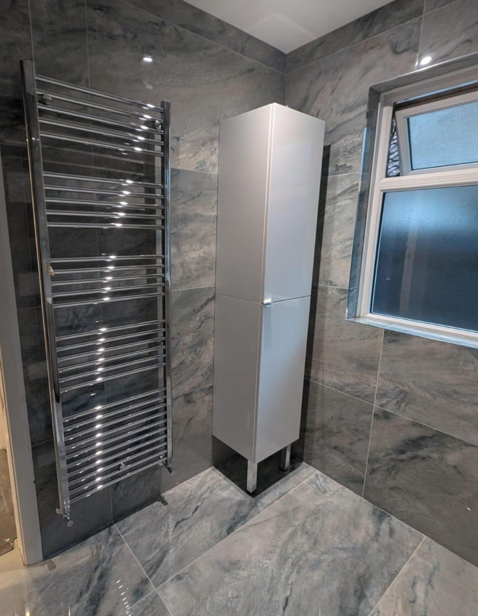 Grey marble bathroom with towel rail and cabinet