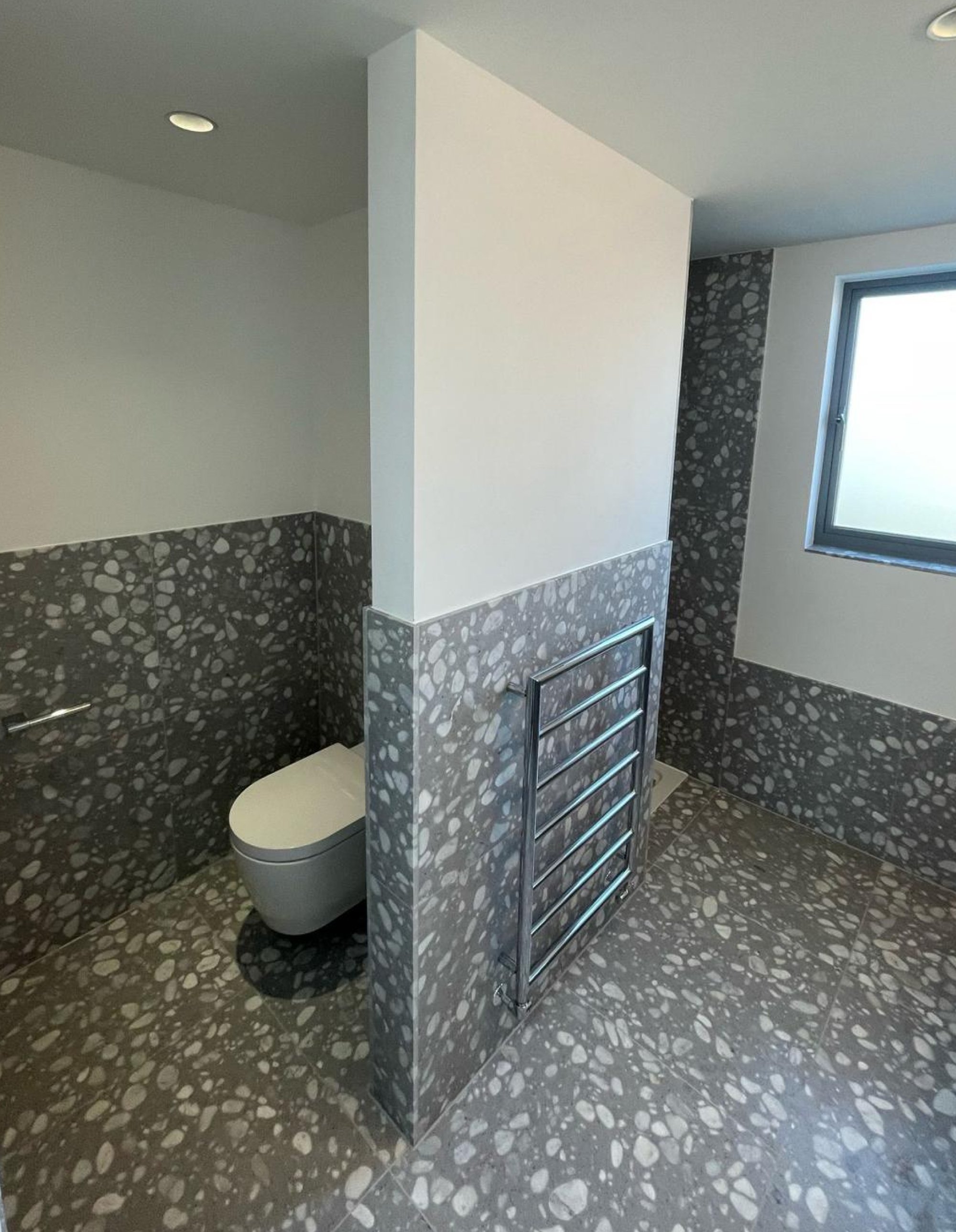 Terrazzo-tiled bathroom with dividing wall