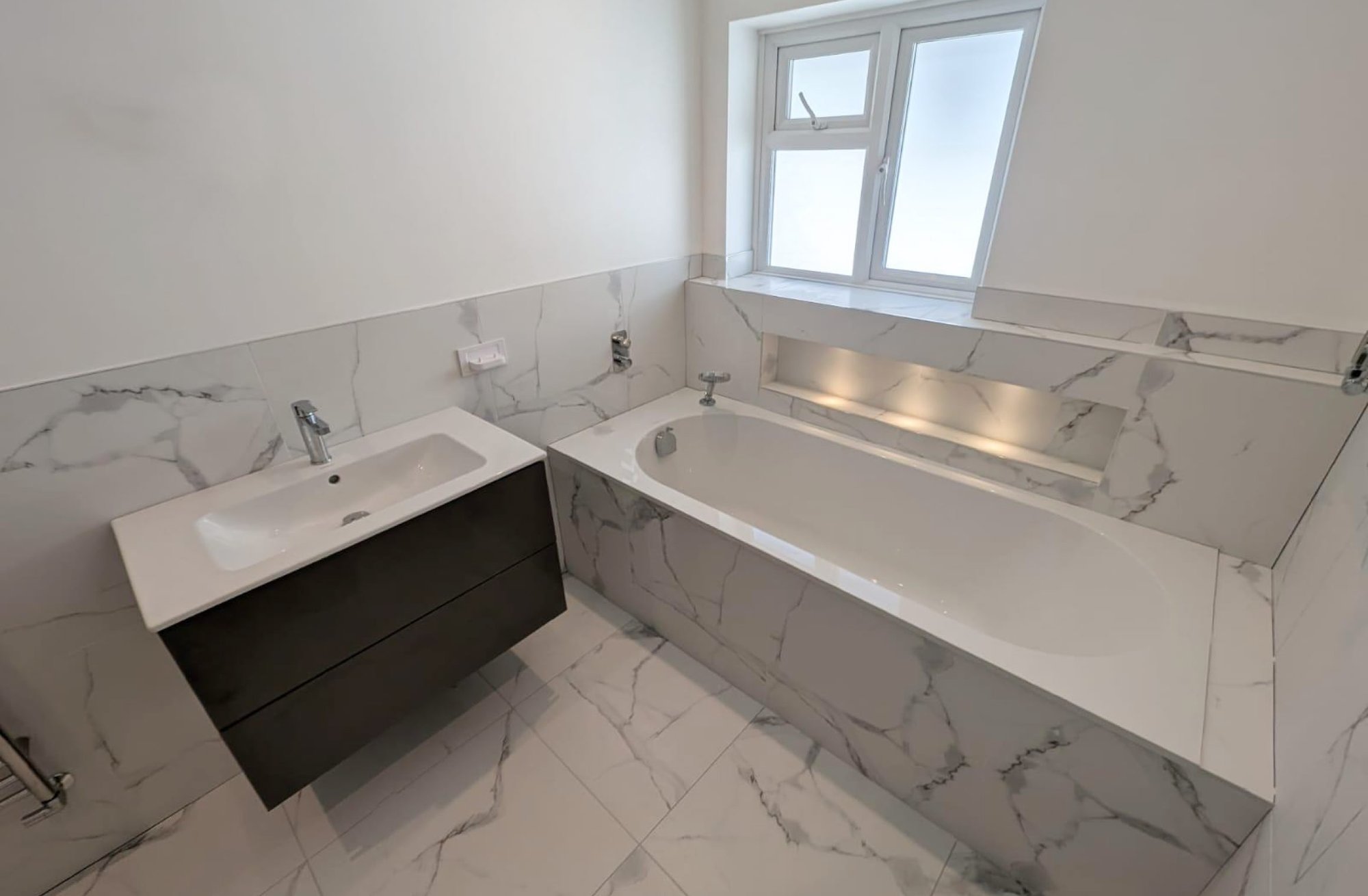 Marble bathroom with inset bathtub and floating vanity