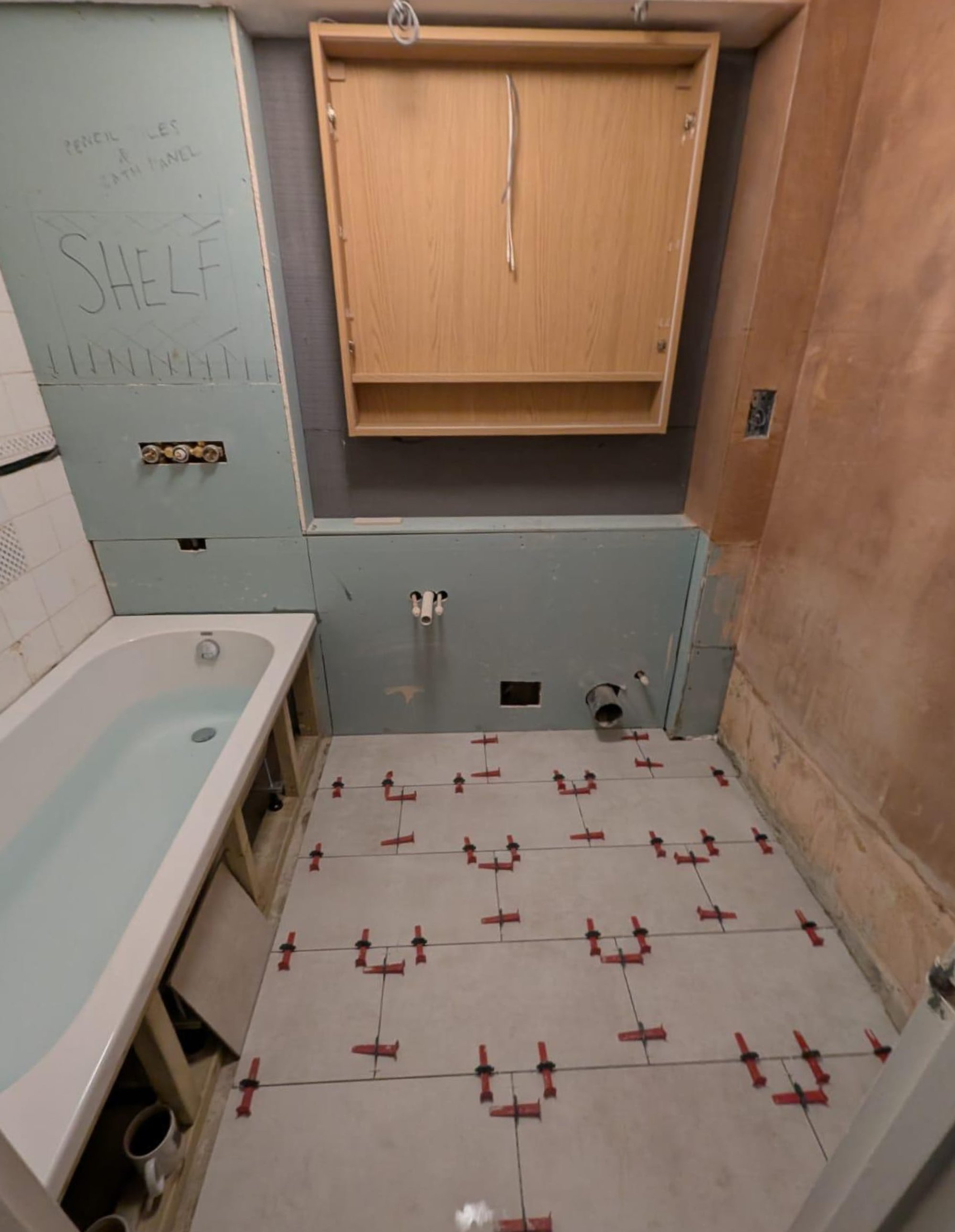 Bathroom renovation with tiled floor and unfinished walls