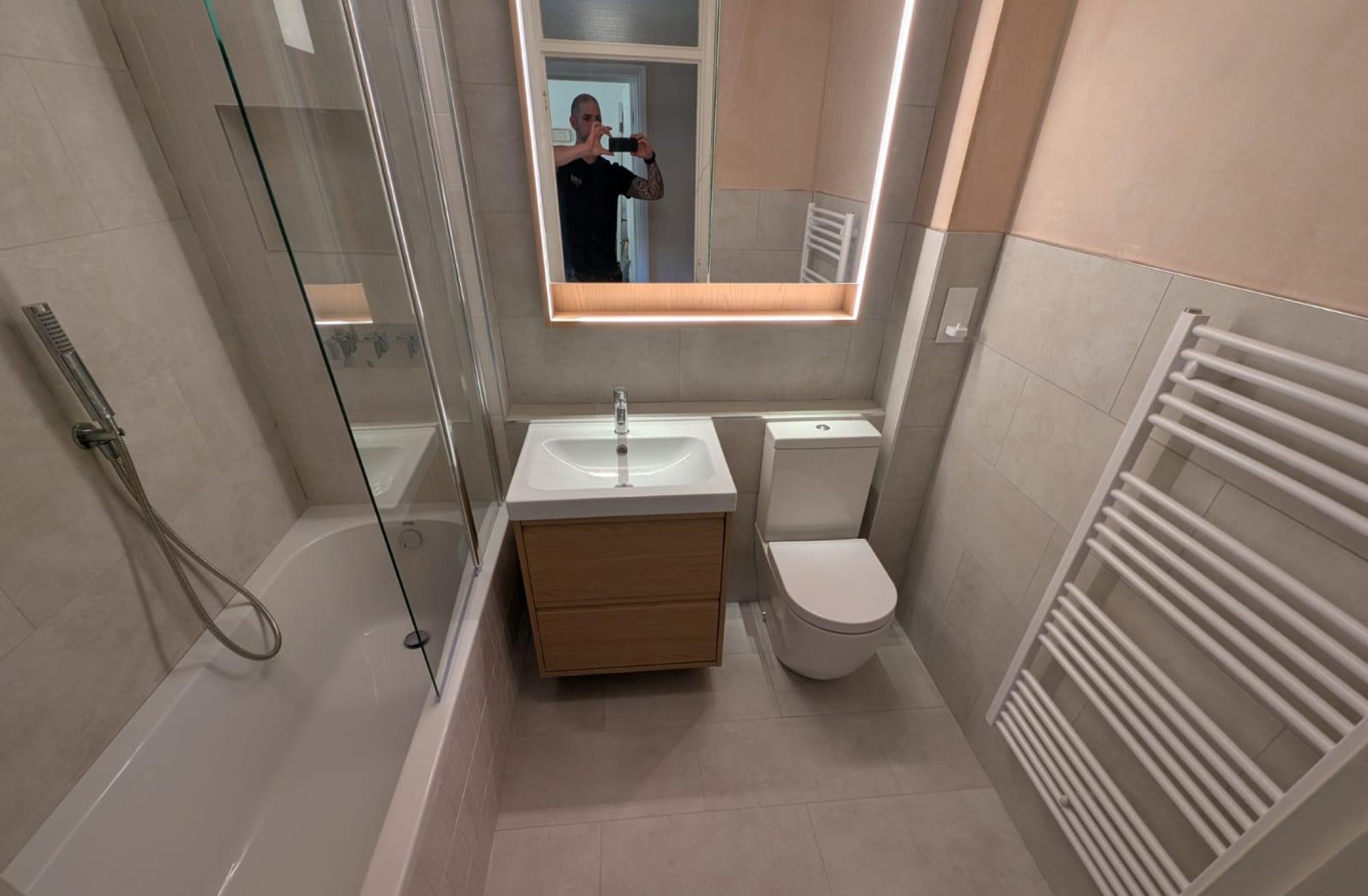 Modern grey bathroom with tub and illuminated mirror