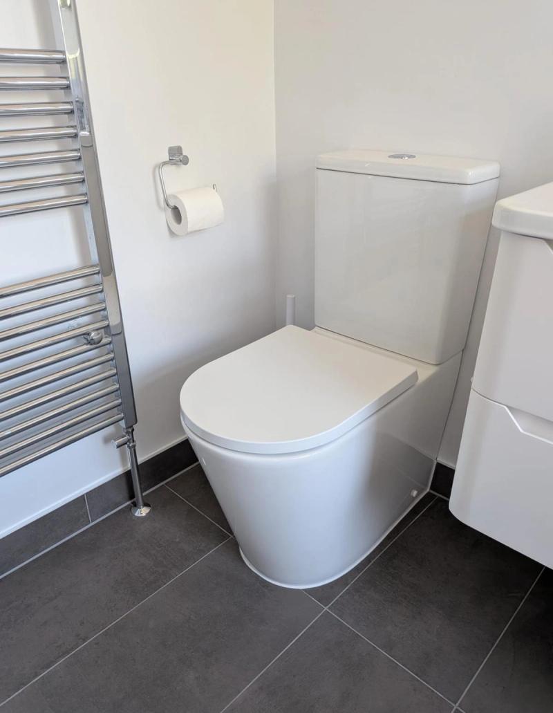 Toilet beside chrome towel radiator