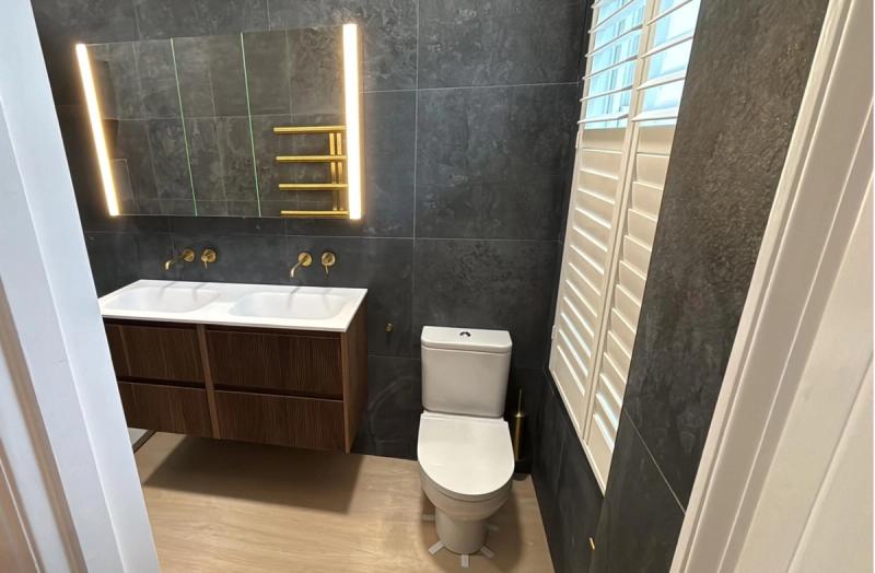 Dark grey bathroom with double vanity and toilet
