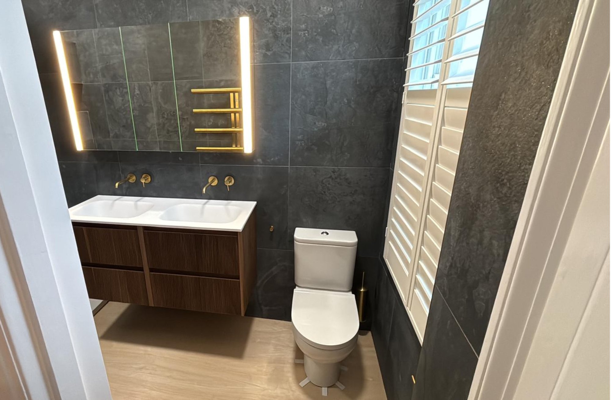 Dark grey bathroom with double vanity and toilet