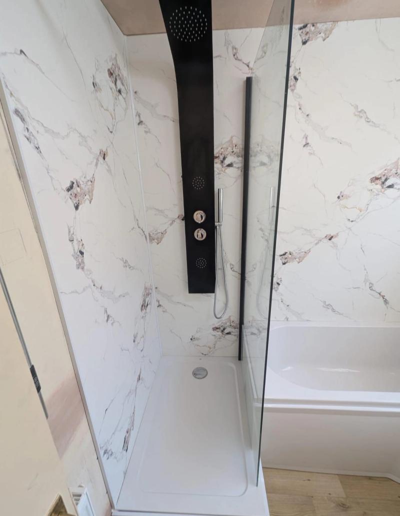 Black shower panel beside corner bathtub
