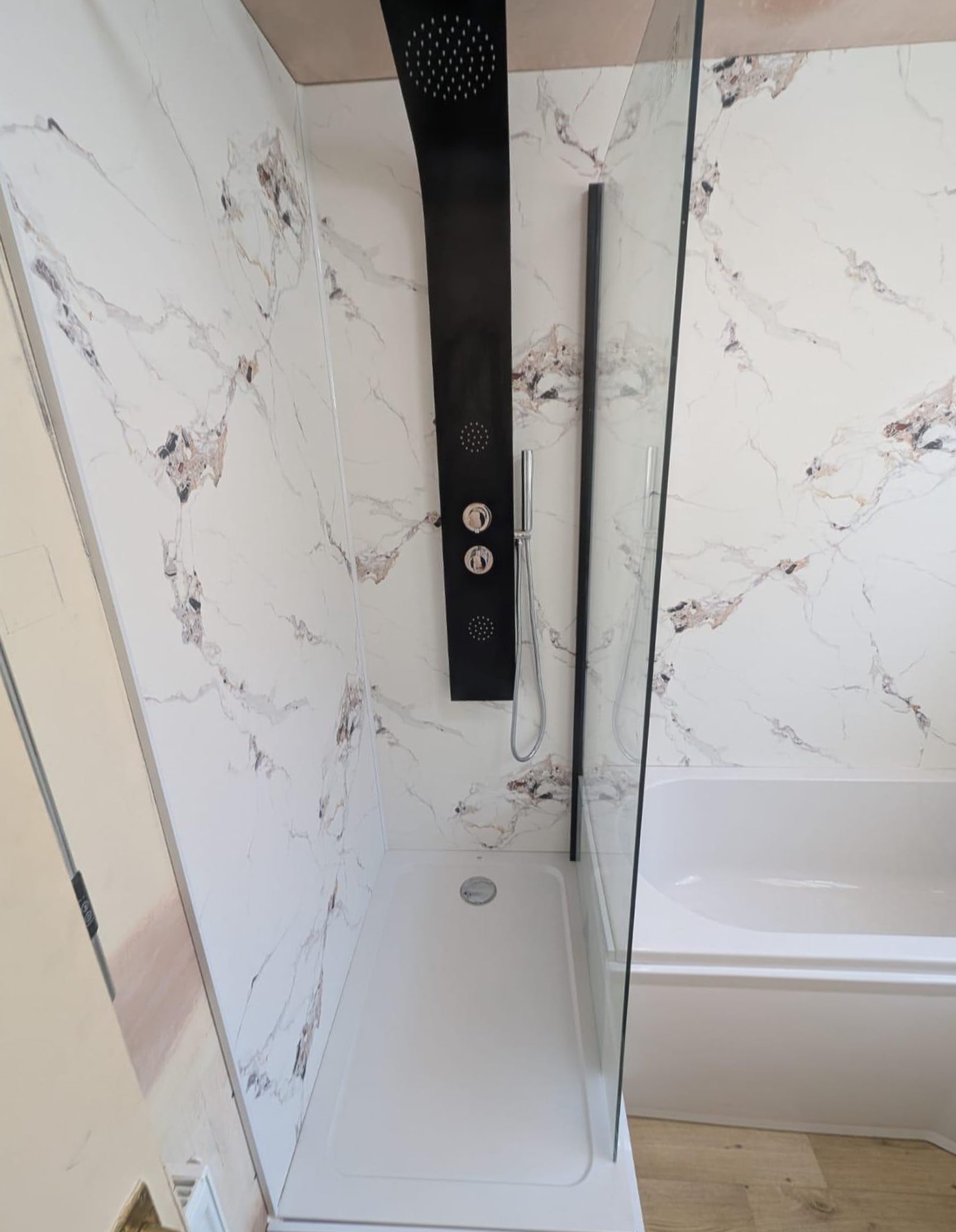 Black shower panel beside corner bathtub