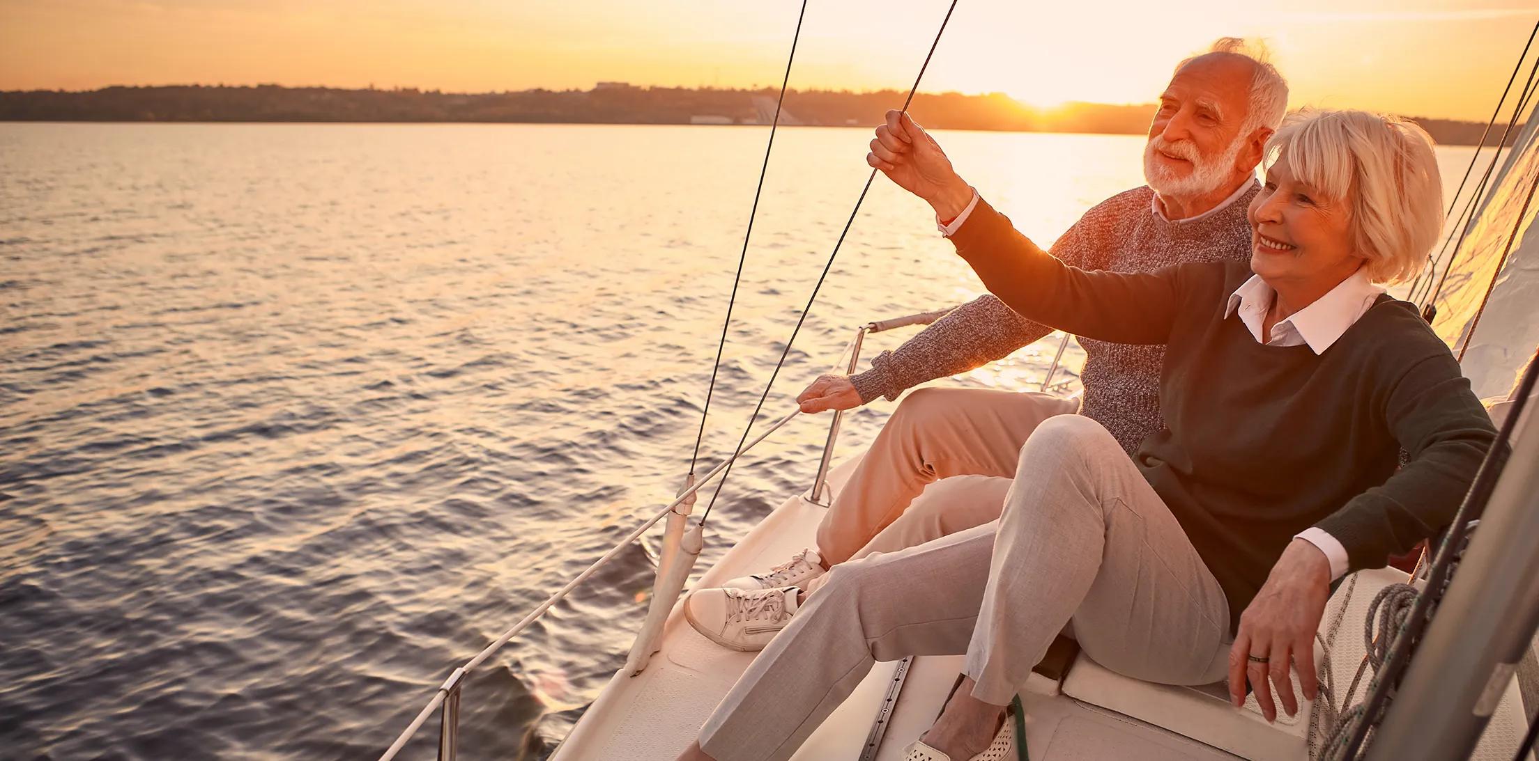 A retired couple sailing together at sunset.