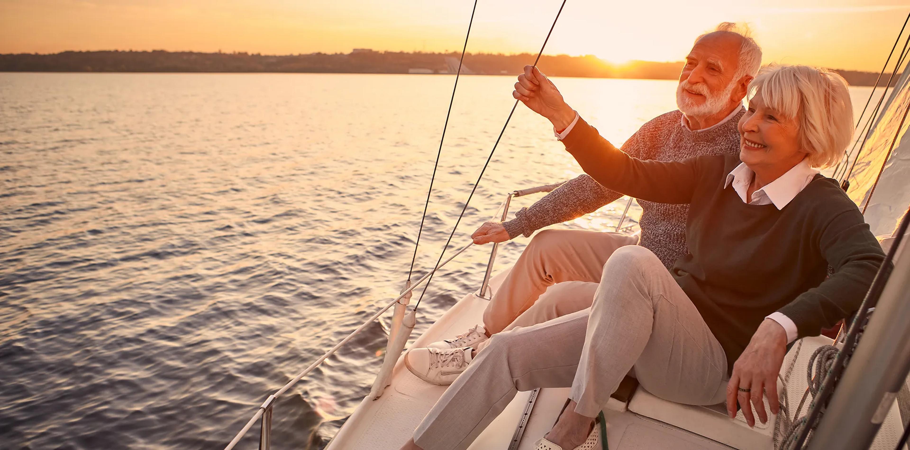 A retired couple sailing together at sunset.