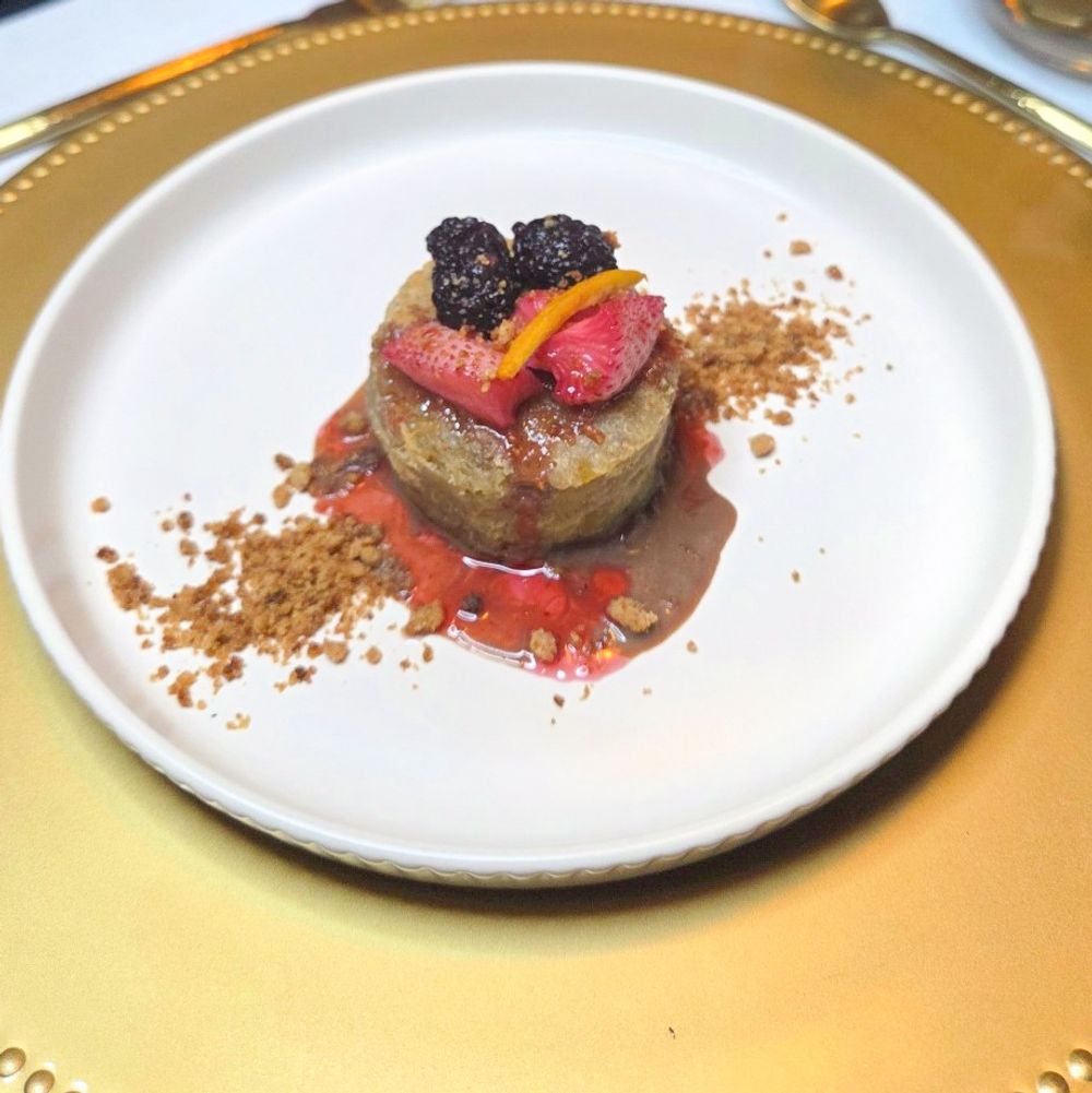 Luxury Caribbean banana coffee cake pudding plated with fresh berries, citrus garnish, and gourmet sauce at an exclusive private dining experience by JWU-trained Chef Kimberly Kee
