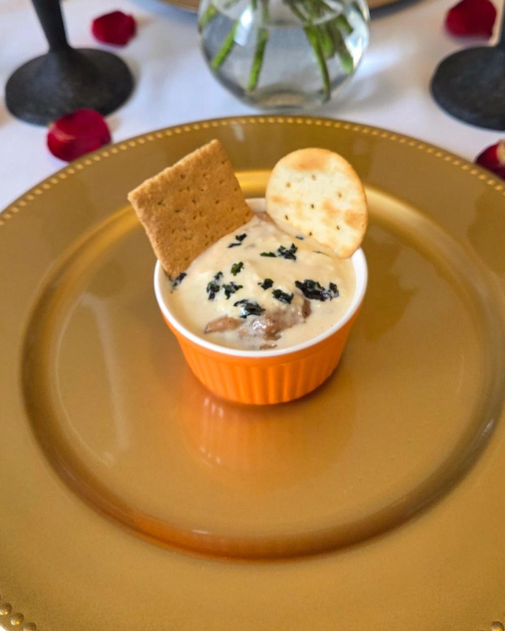 Luxury private dining starter: Toasted Oatmeal by Chef Kimberly Kee of Saucy Kim K, featuring ginger crème fraîche and cookie butter yogurt, served in a vibrant ramekin on an elegant gold charger. High-end Caribbean fusion catering serving Newport RI, Boston MA, and Greenwich CT.