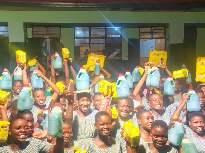 Schoolchildren holding up containers and packets handed out by the foundation