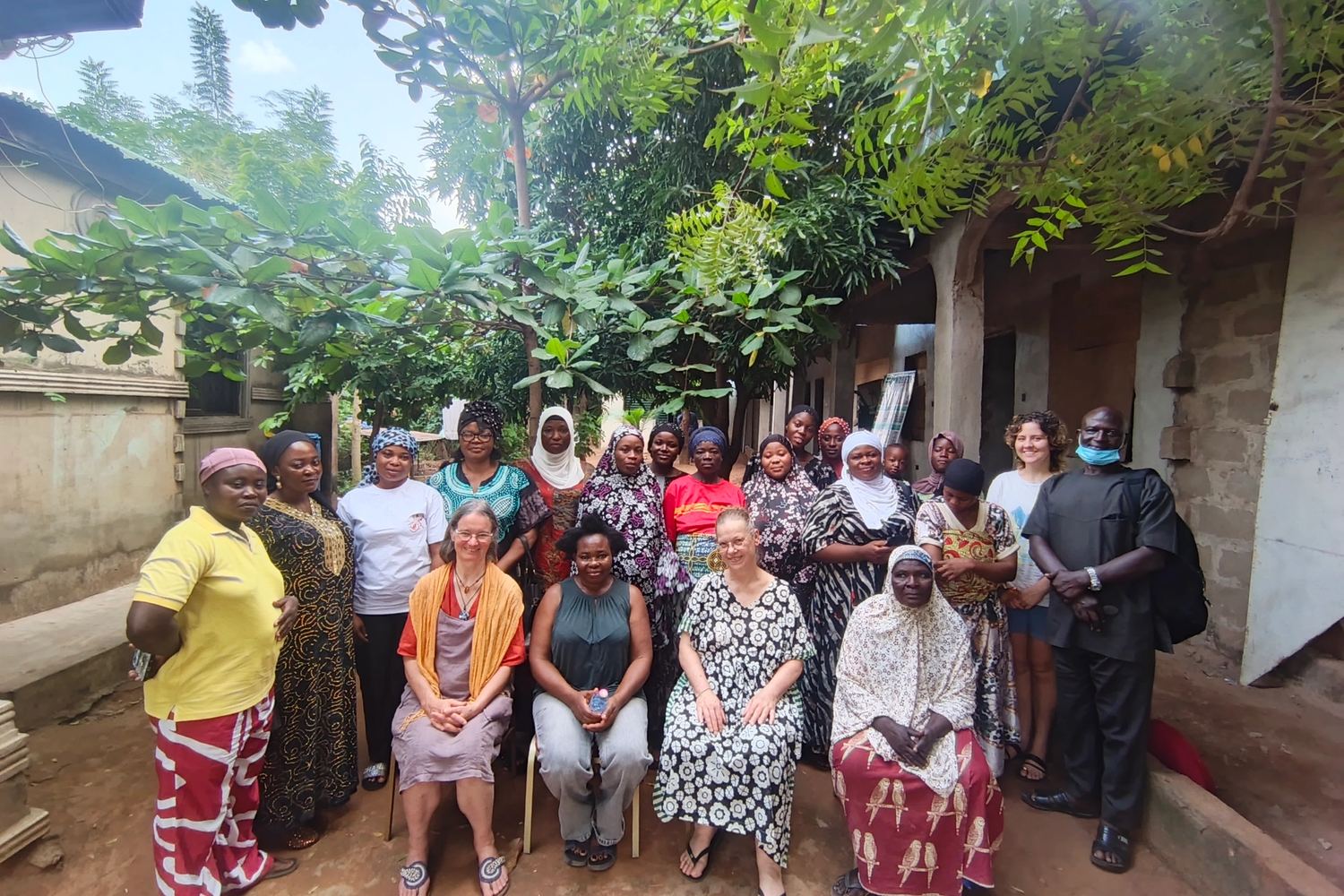 Women of the foundation with visiting partners outside a community building