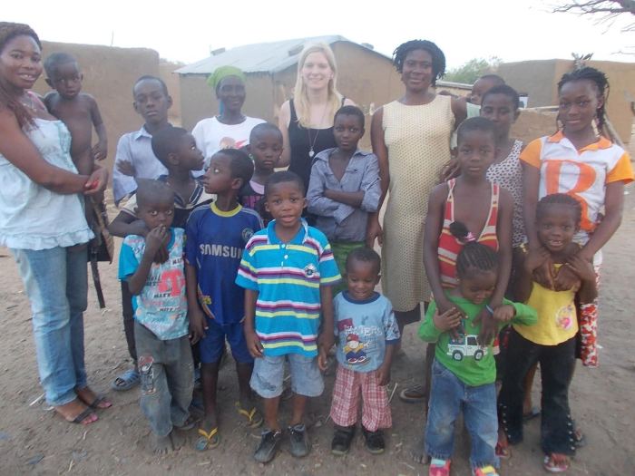 Children and women of a community gathered with a visitor