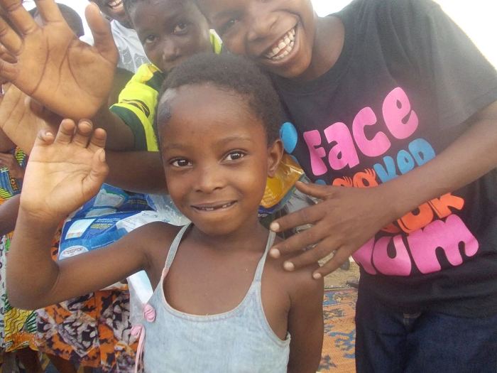 Children smiling and waving during a community visit
