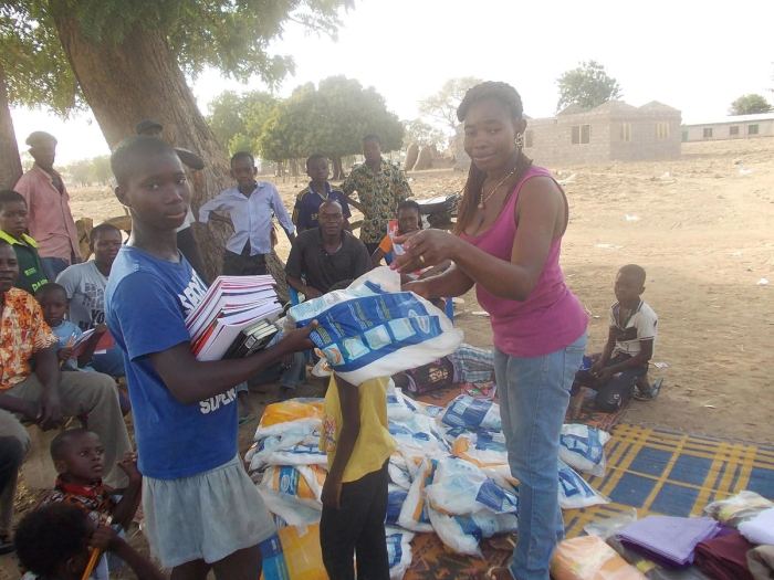 Exercise books and supplies being handed out beneath a tree