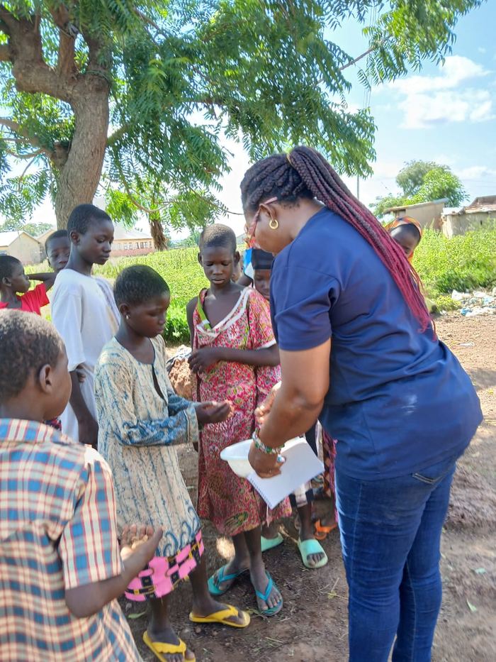 A volunteer serving food to children from a basin